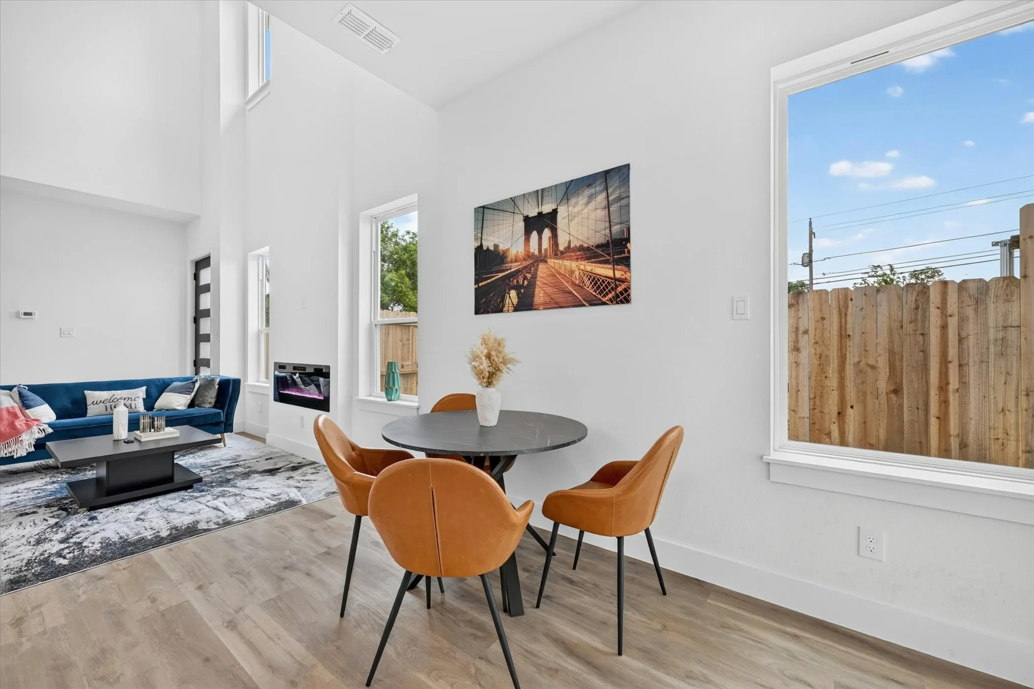 Open-concept living area with high ceilings, wood-finish flooring, and multiple windows