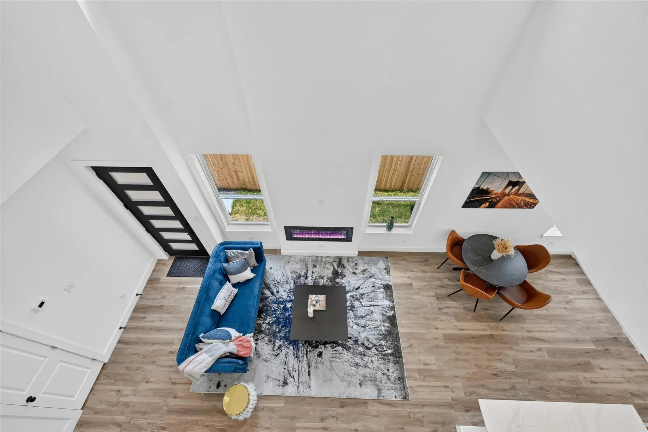 Vaulted ceilings with skylights, wood-finish flooring, and a linear electric fireplace