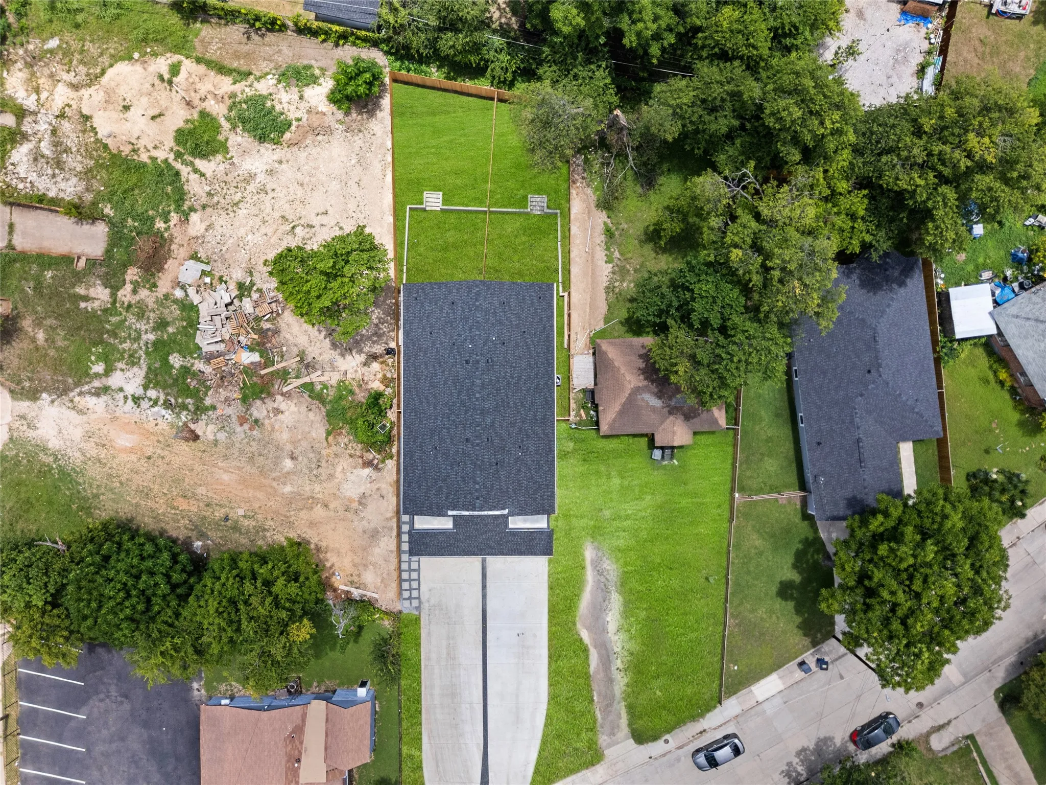 Newly constructed property featuring a dark shingle roof, a concrete driveway, and a spacious, manicured lawn