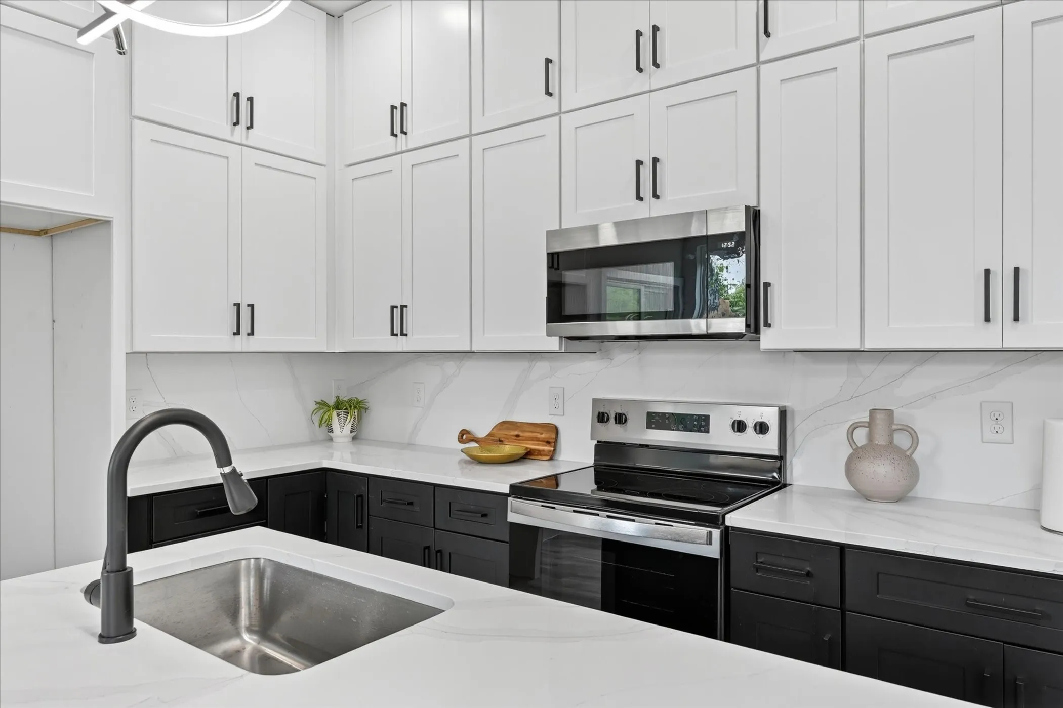 Contemporary kitchen featuring white upper cabinetry and black lower cabinetry with matte black hardware