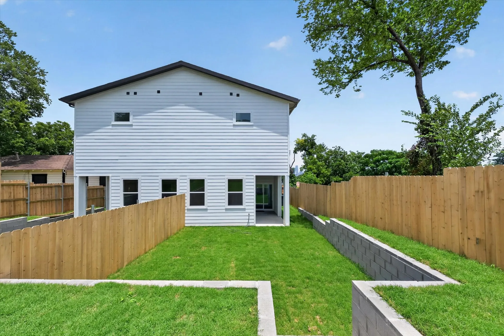 Two-story residence with white siding, a dark roof, and multiple windows