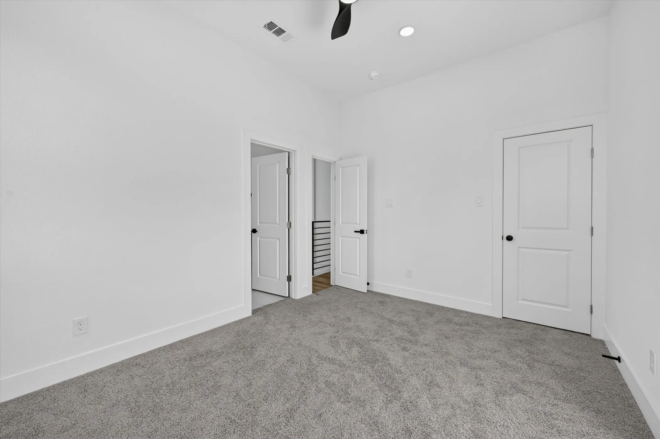 Carpeted room with white walls, a black ceiling fan, and recessed lighting