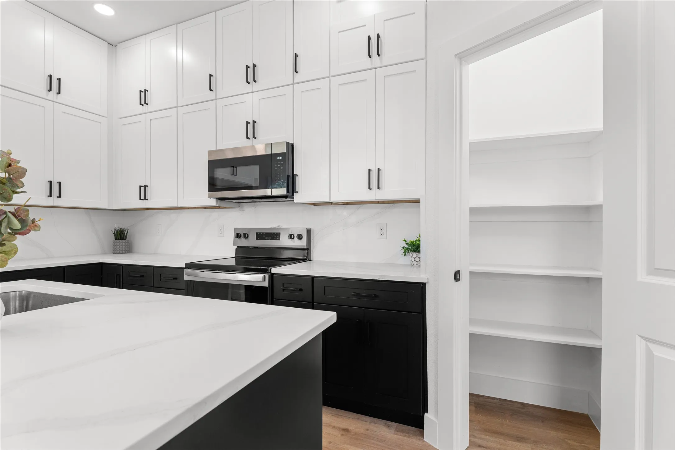 Kitchen featuring a two-tone cabinetry design, stainless steel appliances, and an expansive island with a stainless steel sink