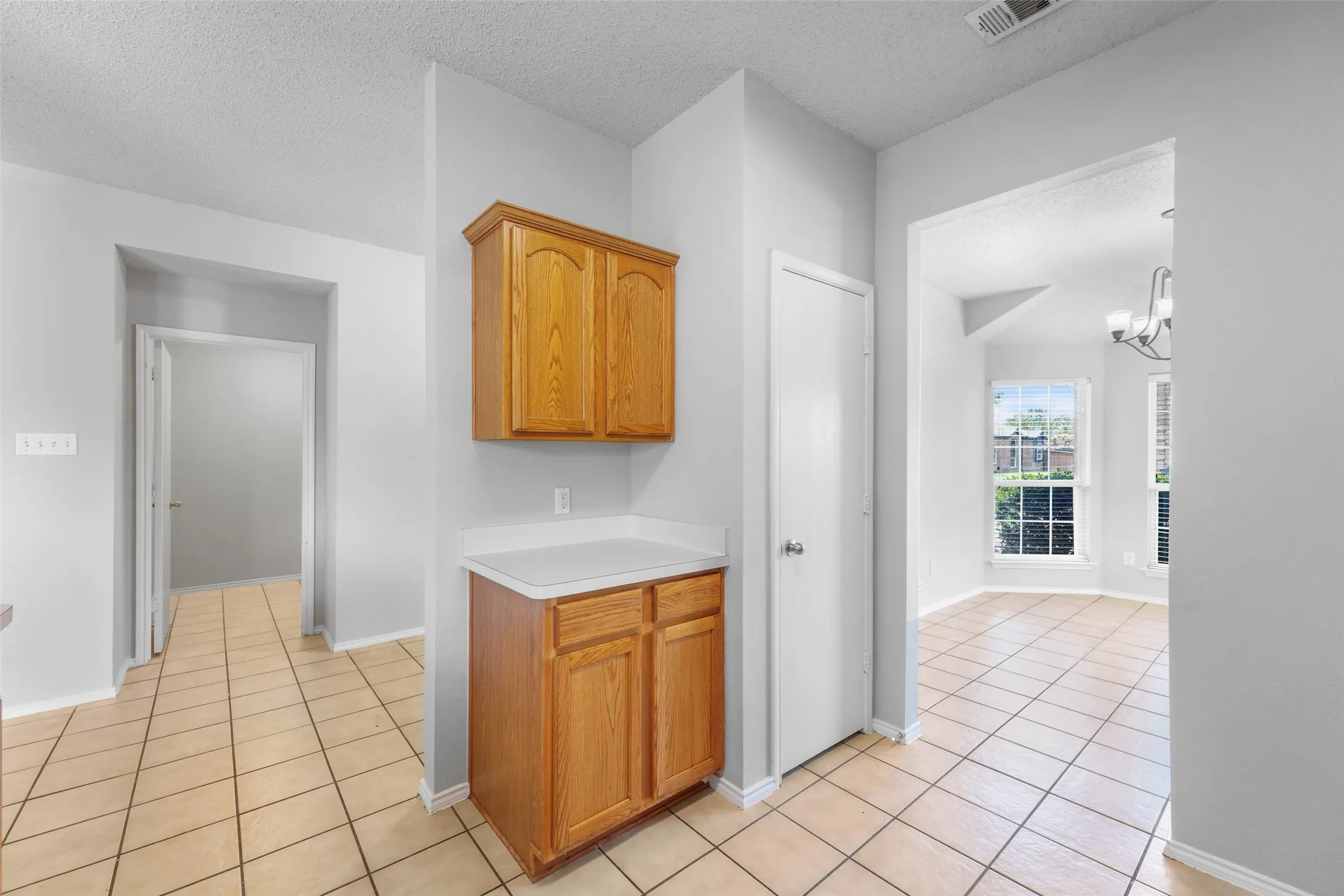 Built-in wood-finish cabinetry with white countertop, square tile flooring, and white interior doors
