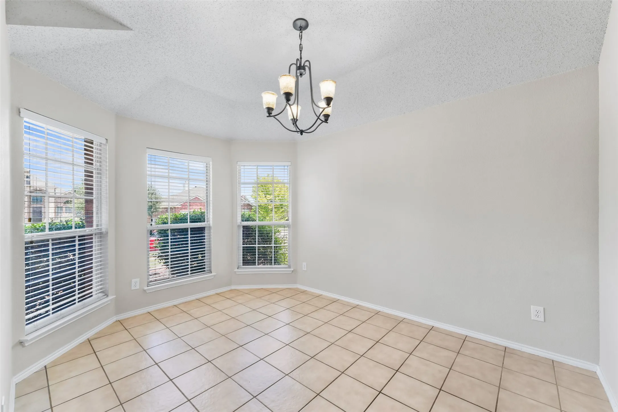 Bay window area with tile flooring and a multi-light chandelier