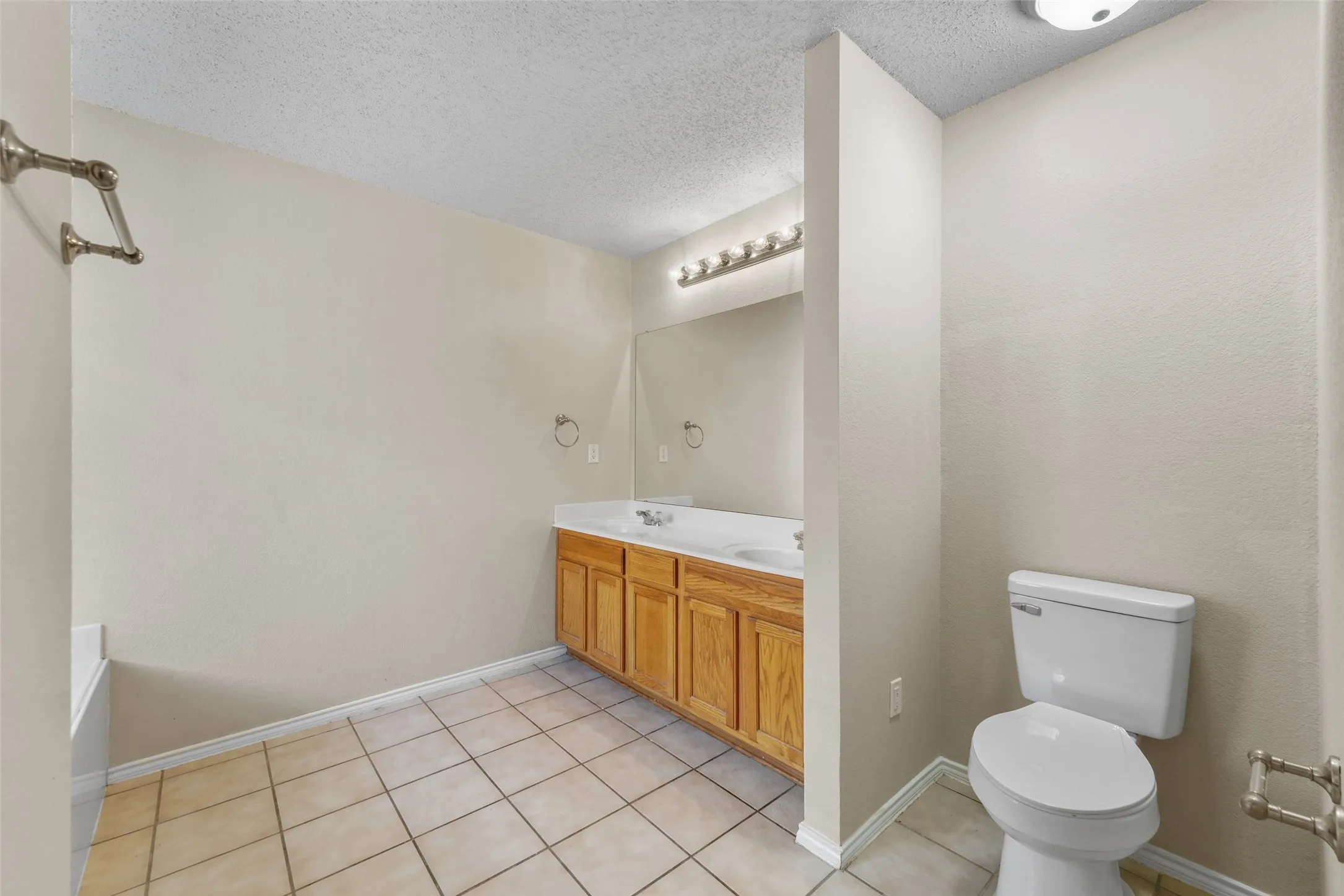 Bathroom featuring a double vanity with wood-finish cabinetry, a large mirror, and a white countertop