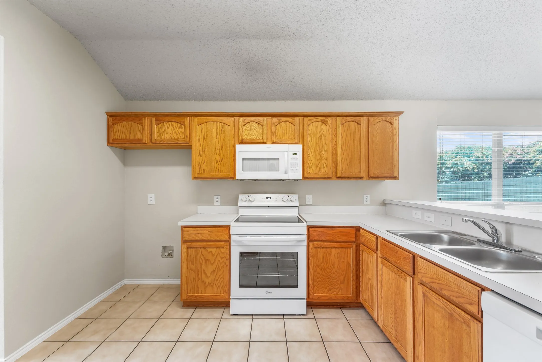 Kitchen featuring wood-finish cabinetry, white countertops, and tile flooring