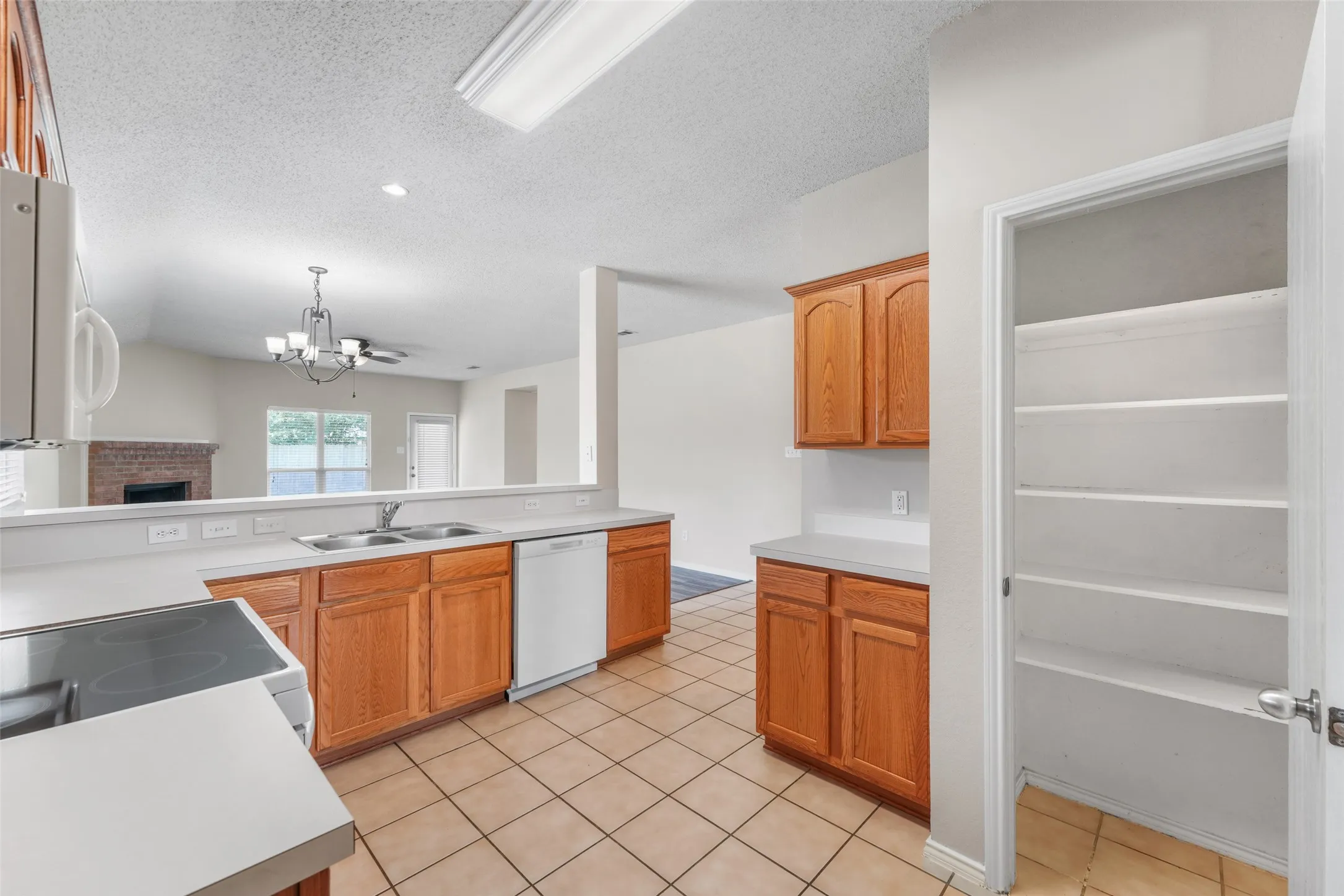 Kitchen featuring wood cabinetry, solid surface countertops, tile flooring, and integrated pantry shelving