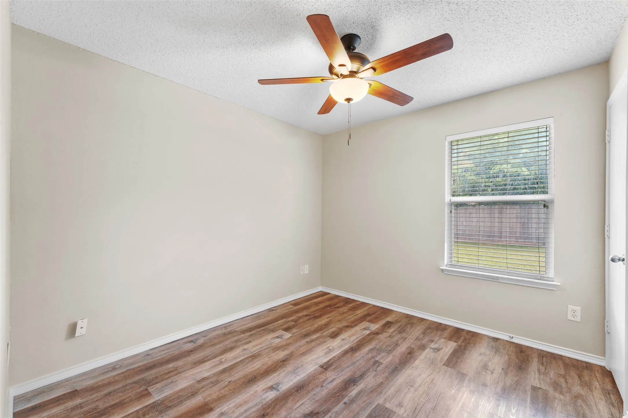 Interior room featuring wood-finish flooring, neutral wall paint, and a ceiling fan with integrated lighting
