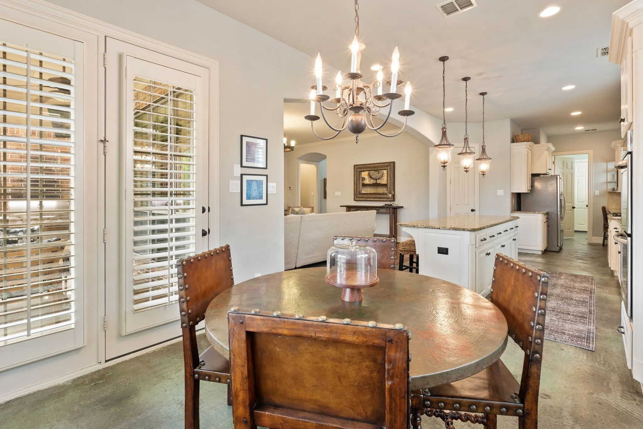 Dining area featuring a decorative chandelier, French doors with plantation shutters, and polished concrete flooring
