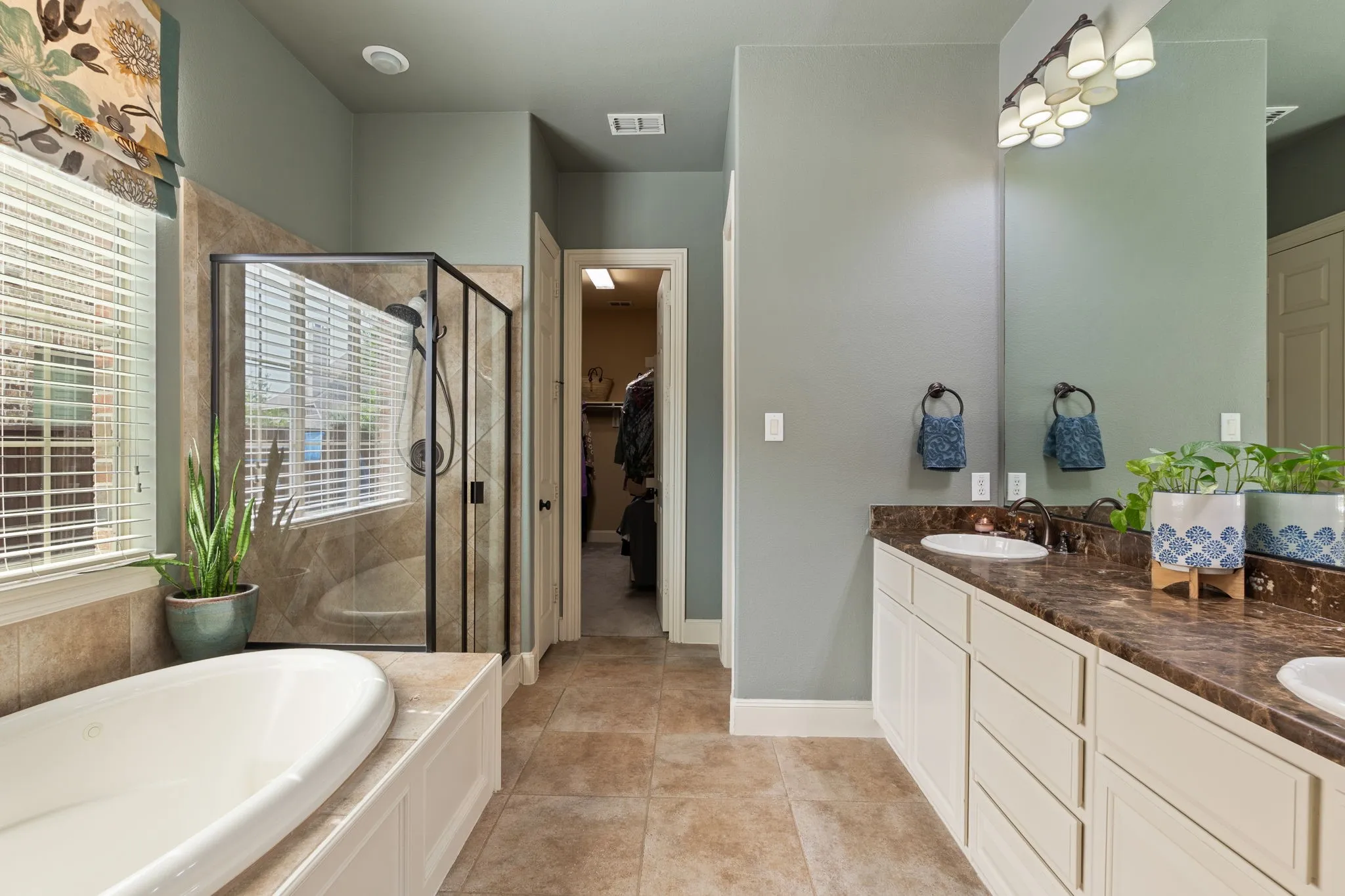 Expansive bathroom featuring a dual vanity with undermount sinks, a built-in garden tub, and a separate glass-enclosed shower