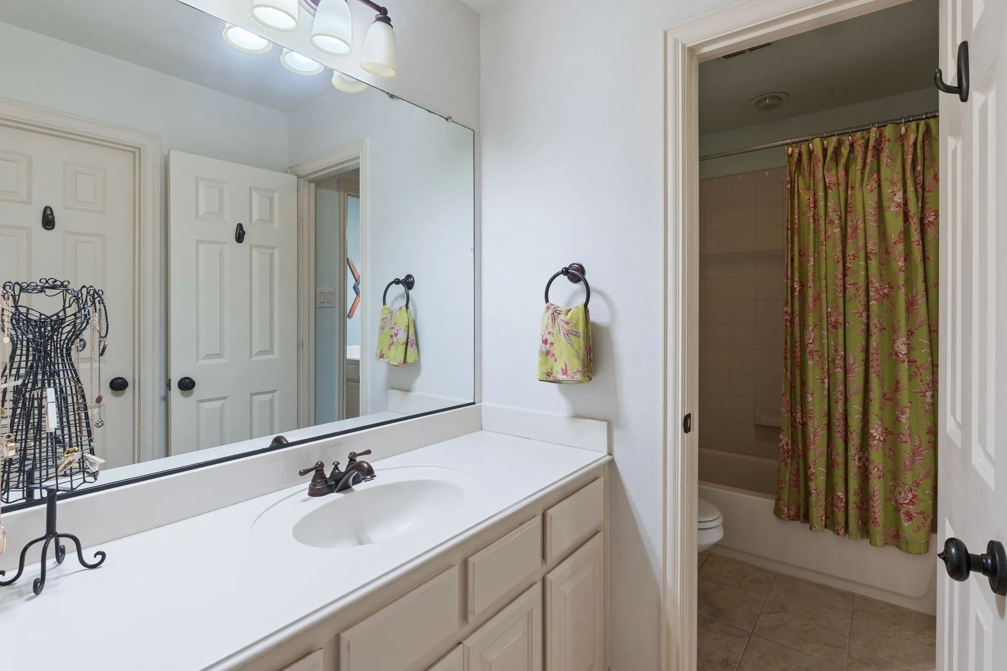 Bathroom featuring an integrated sink with a bronze-finish faucet, a large vanity mirror, and a wall-mounted light fixture
