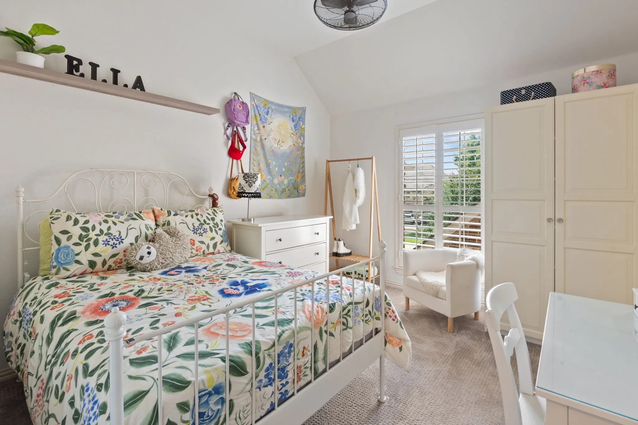 Vaulted ceiling bedroom featuring plush carpeting, plantation shutters, built-in cabinetry, a ceiling fan, and ample natural light