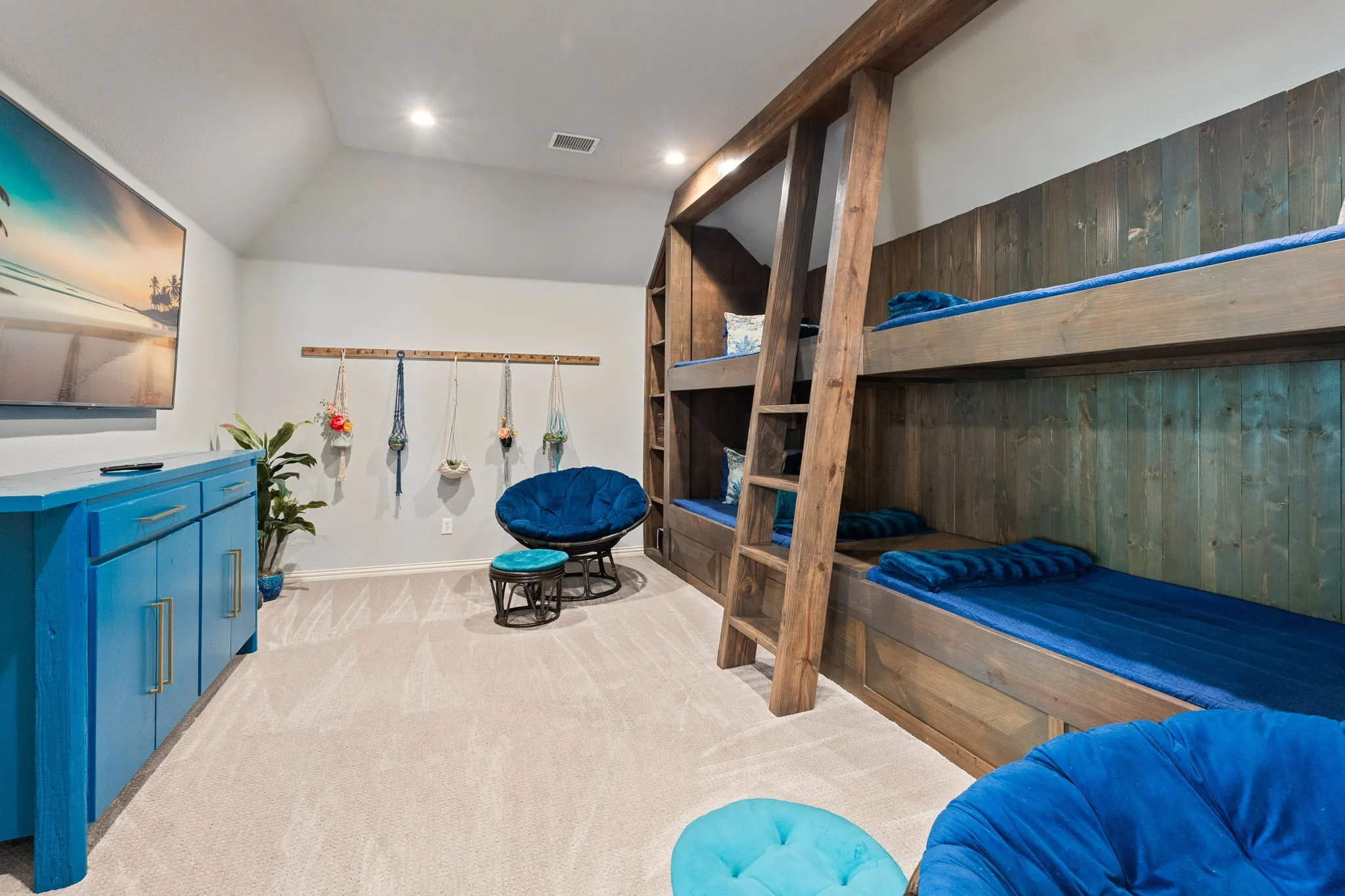Custom built-in bunk beds with wood-finish paneling, a vaulted ceiling, recessed lighting, and light-toned carpeting