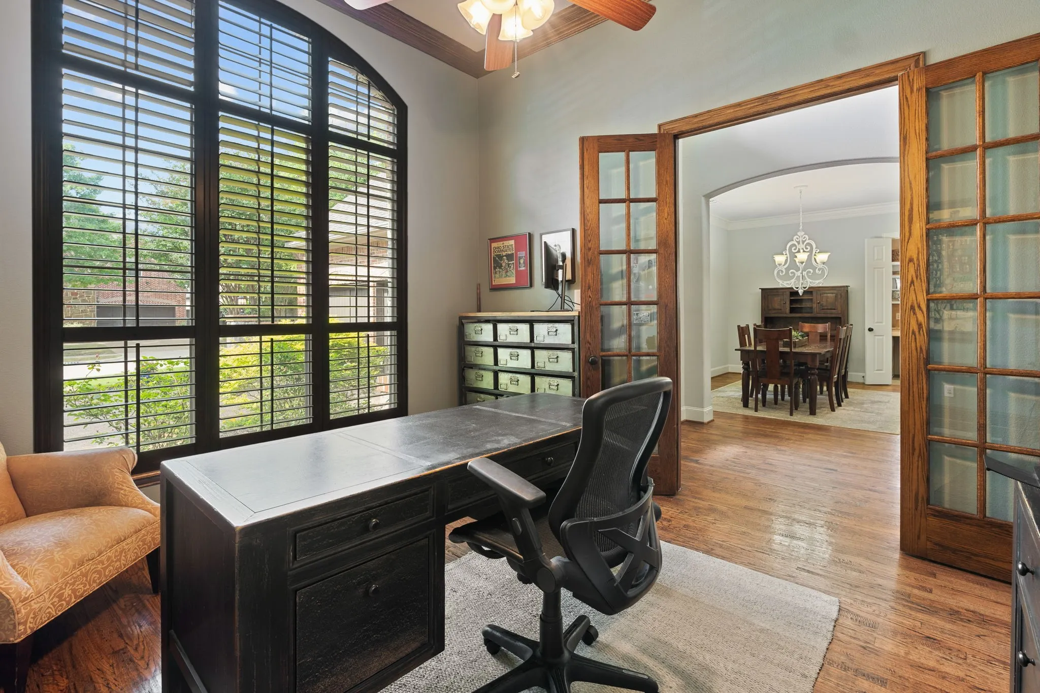 Arch-top window with plantation shutters, wood-finish flooring, and French doors featuring glass panels