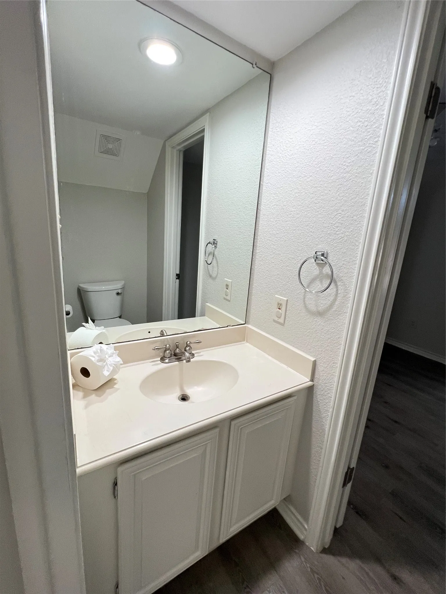 Bathroom vanity with a white countertop and integrated sink, chrome faucet, and white paneled​​‌​​​​‌​​‌‌​‌‌​​​‌‌​‌​‌​‌​​​‌​​ cabinetry