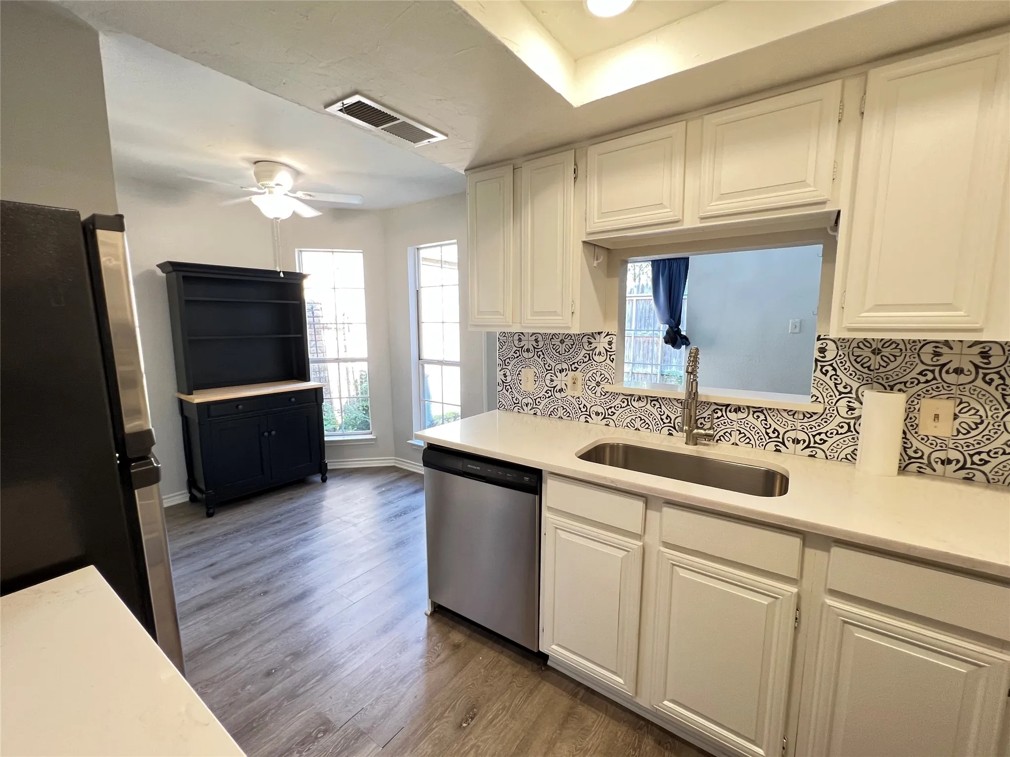 Kitchen area featuring white cabinetry, light countertops, and a decorative tile backsplash