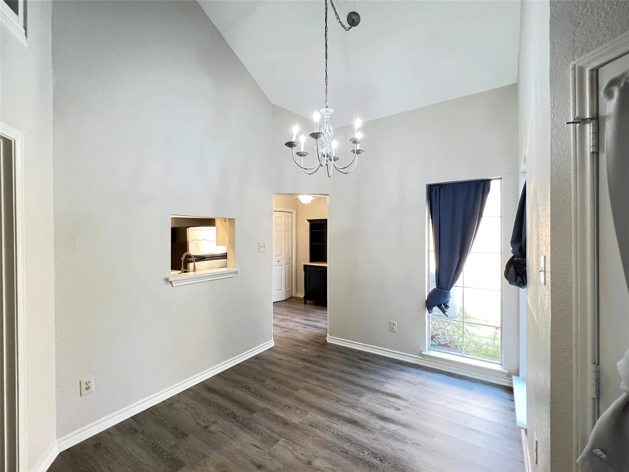 Vaulted ceilings highlight this space featuring wood-finish flooring and a contemporary chandelier