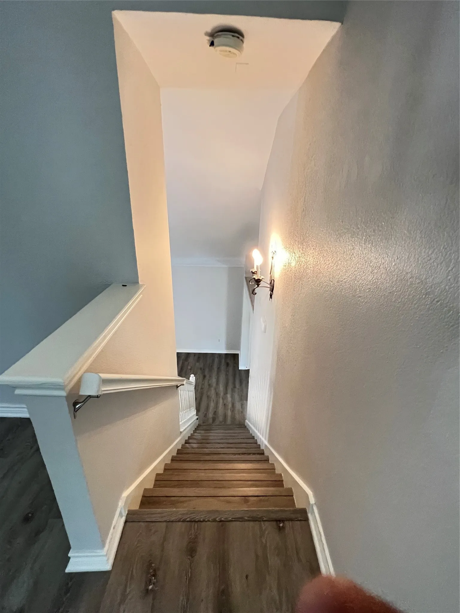 Staircase featuring wood-finish treads and white risers, complemented by a white banister and handrail