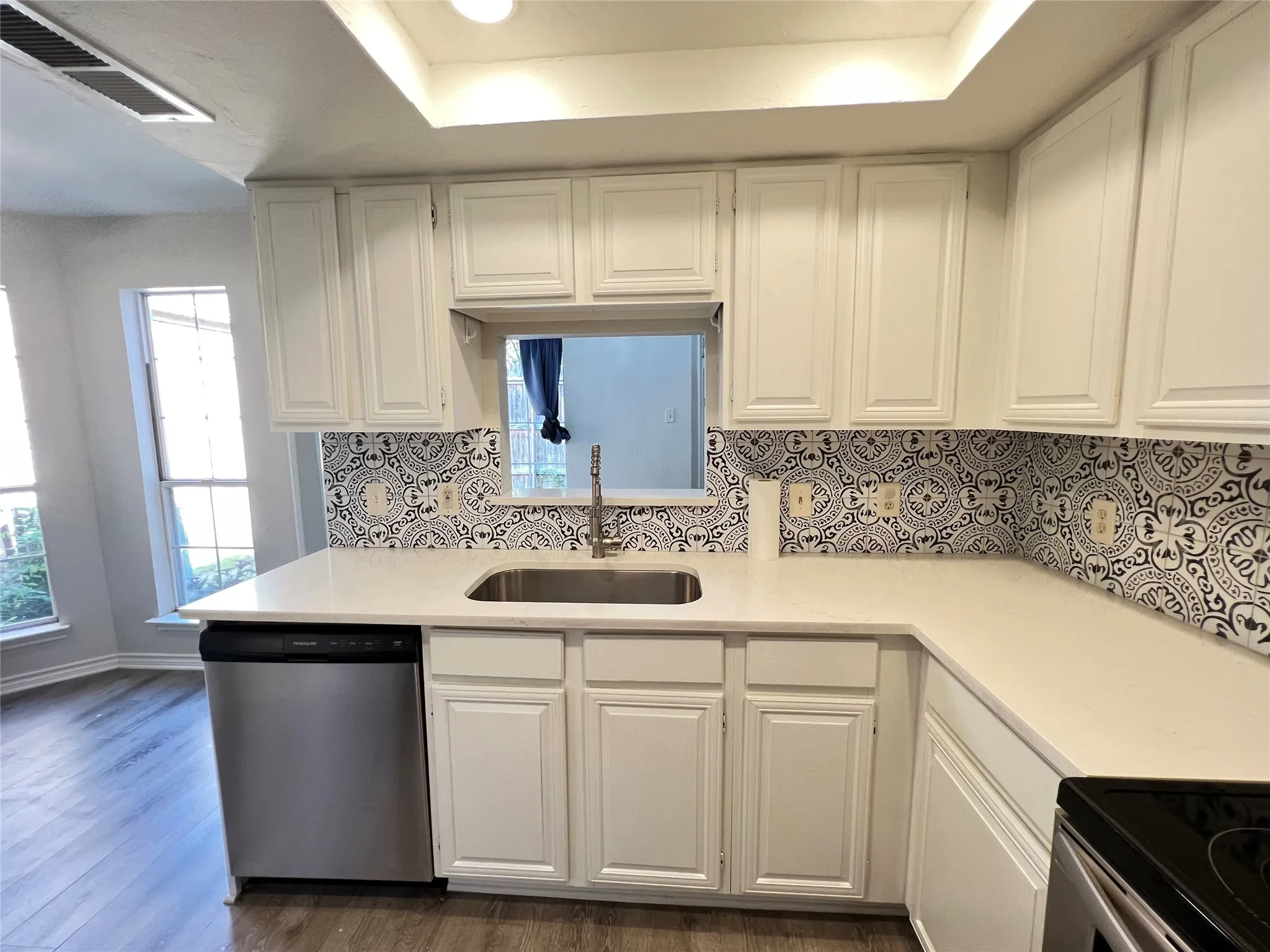 Kitchen featuring white cabinetry, light-toned countertops, a stainless steel sink, and a patterned backsplash