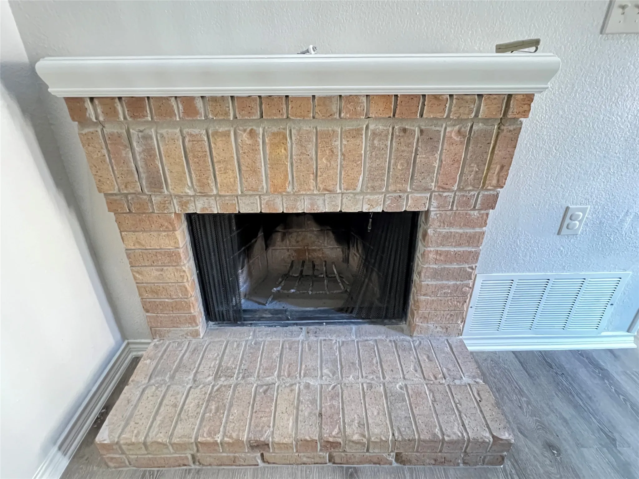 Brick fireplace with a white mantel and hearth