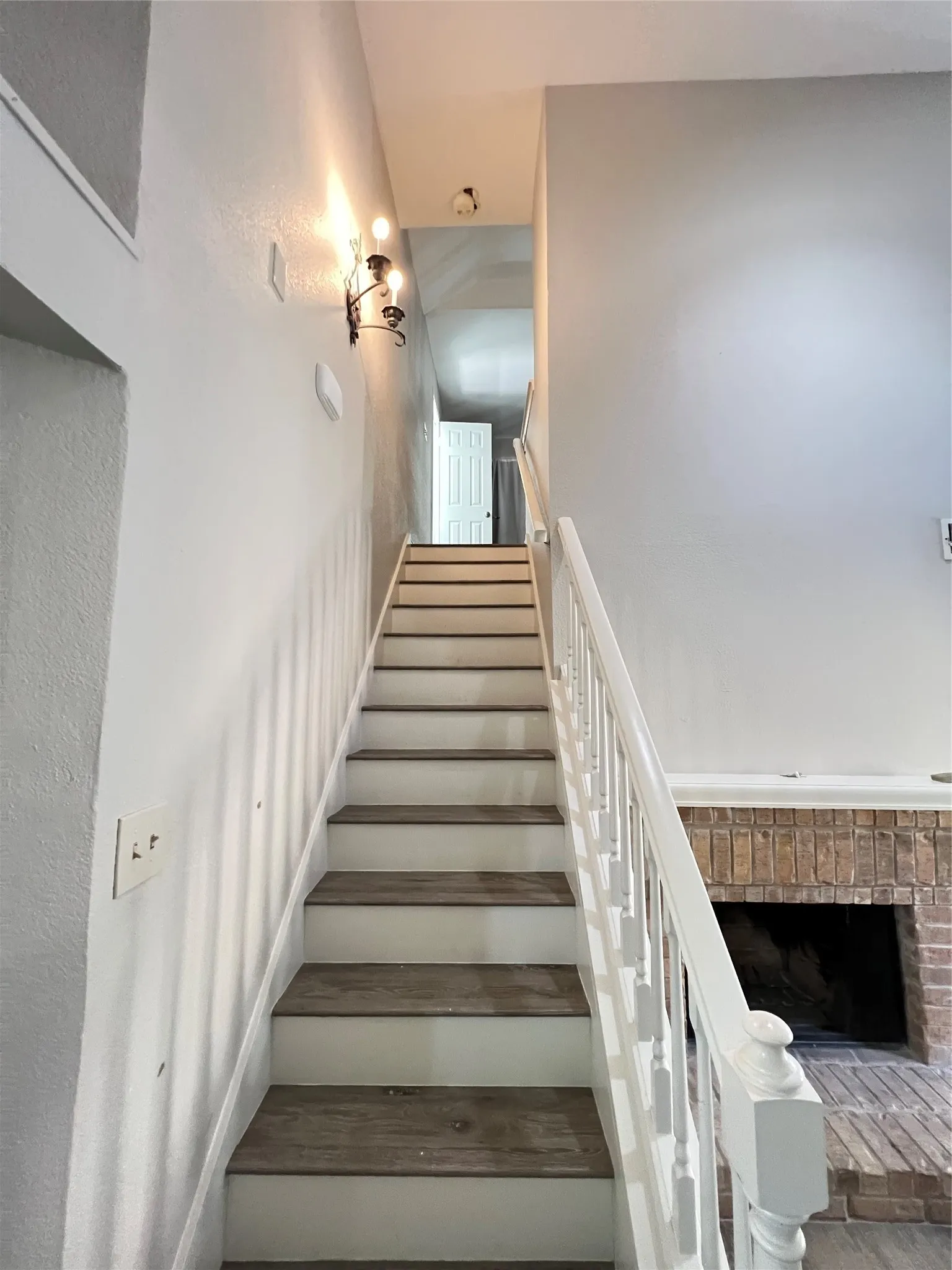 Staircase featuring wood-finish treads and white risers with a painted baluster railing