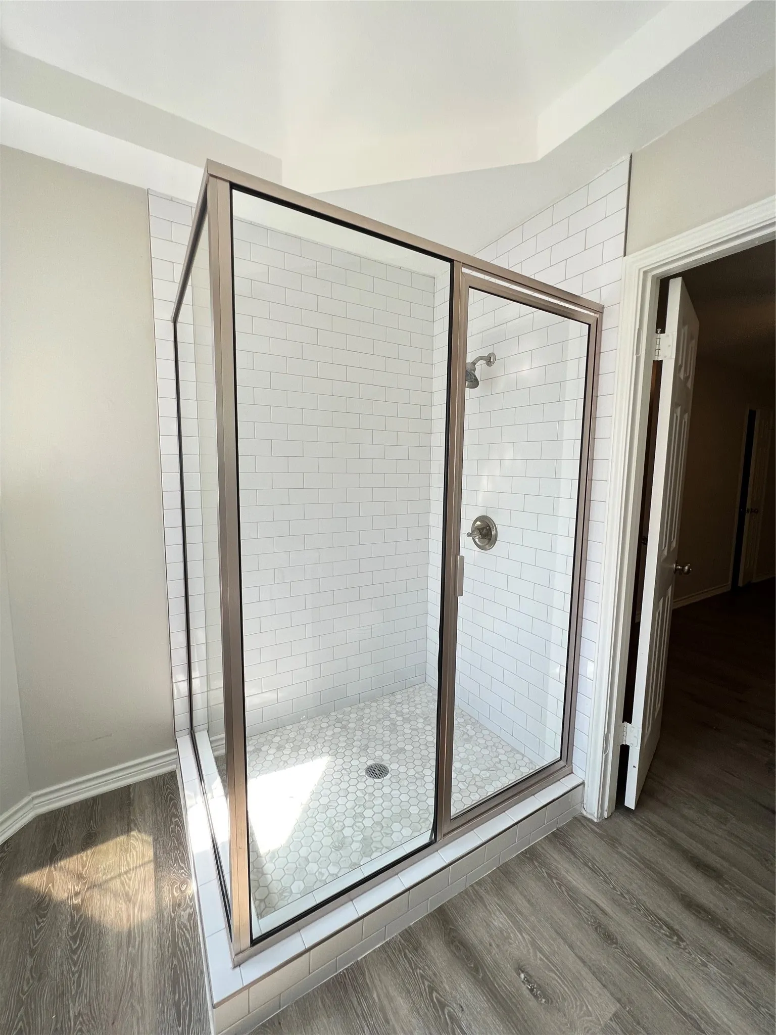 Modern shower enclosure featuring a subway tile surround, clear glass panels, and a hexagonal mosaic tile floor