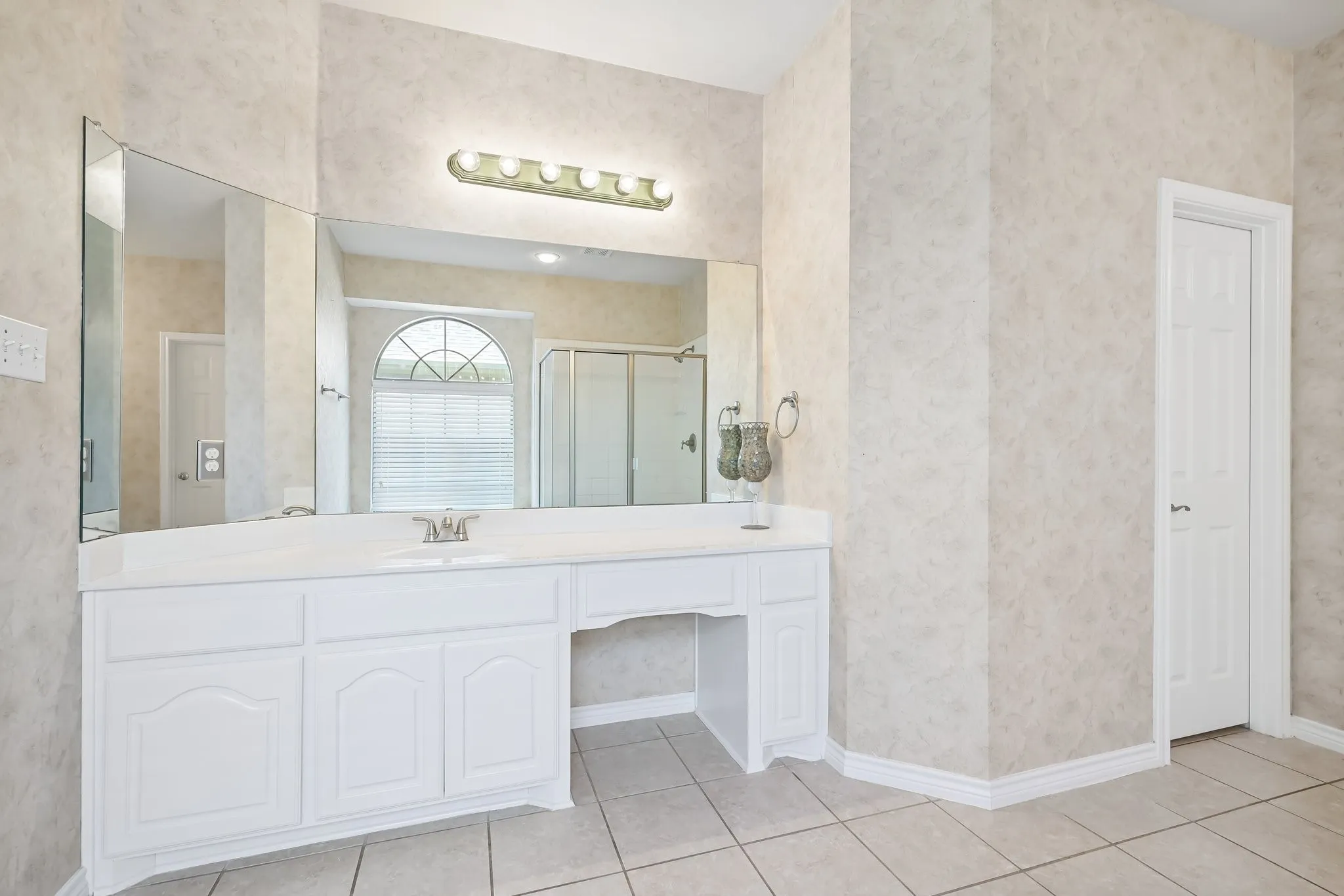Double vanity with an integrated sink, white cabinetry, and a full-width mirror