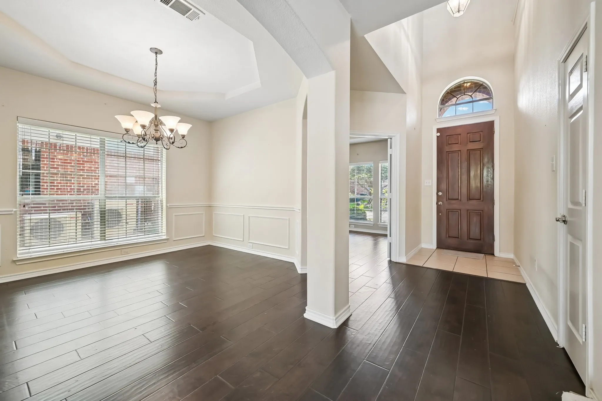 Spacious interior featuring wood-finish flooring, a tray ceiling, and wainscoting