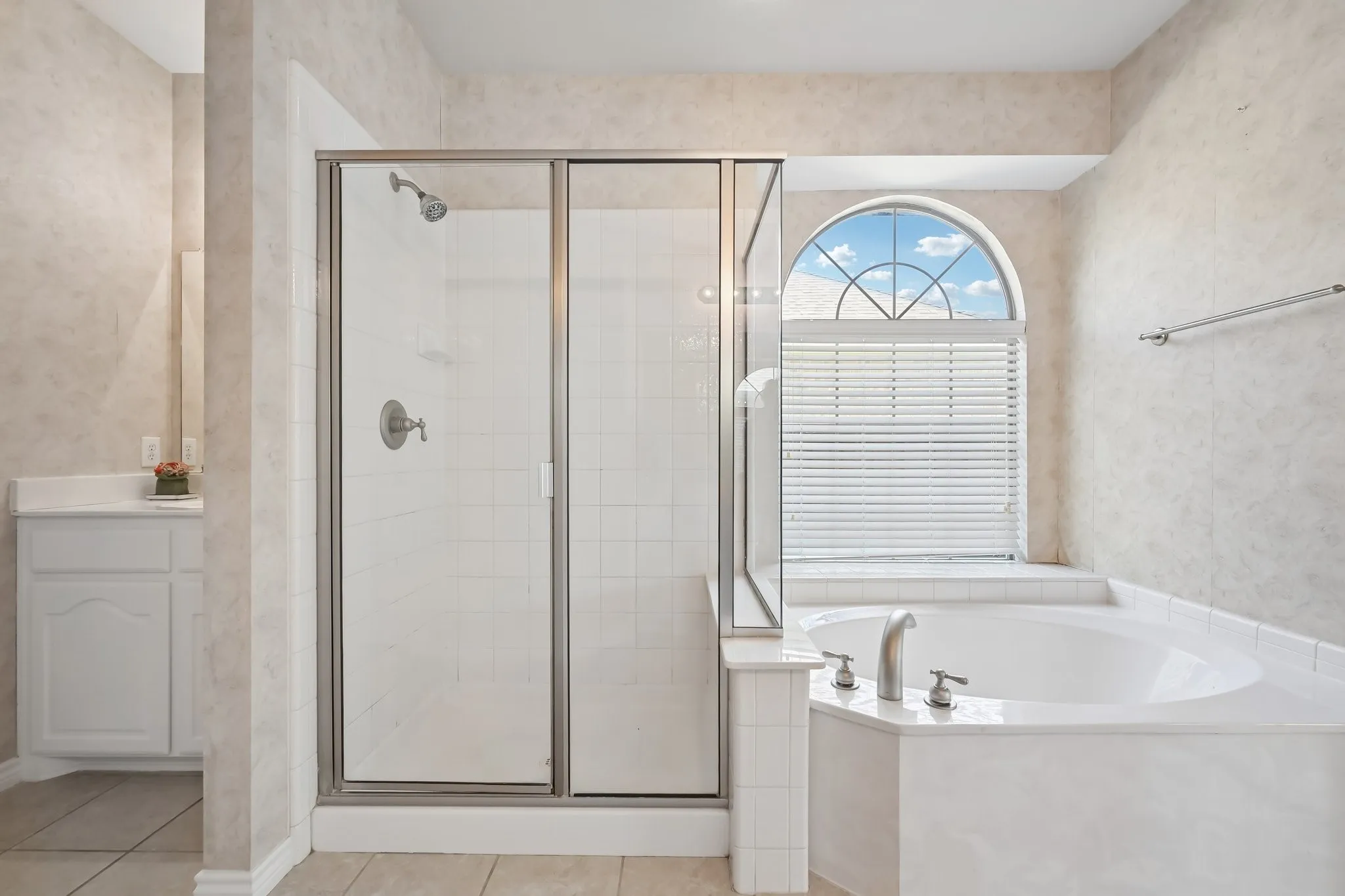 Bathroom featuring a built-in soaking tub with brushed nickel fixtures, a framed glass shower enclosure with a tile surround, and a vanity with a white countertop