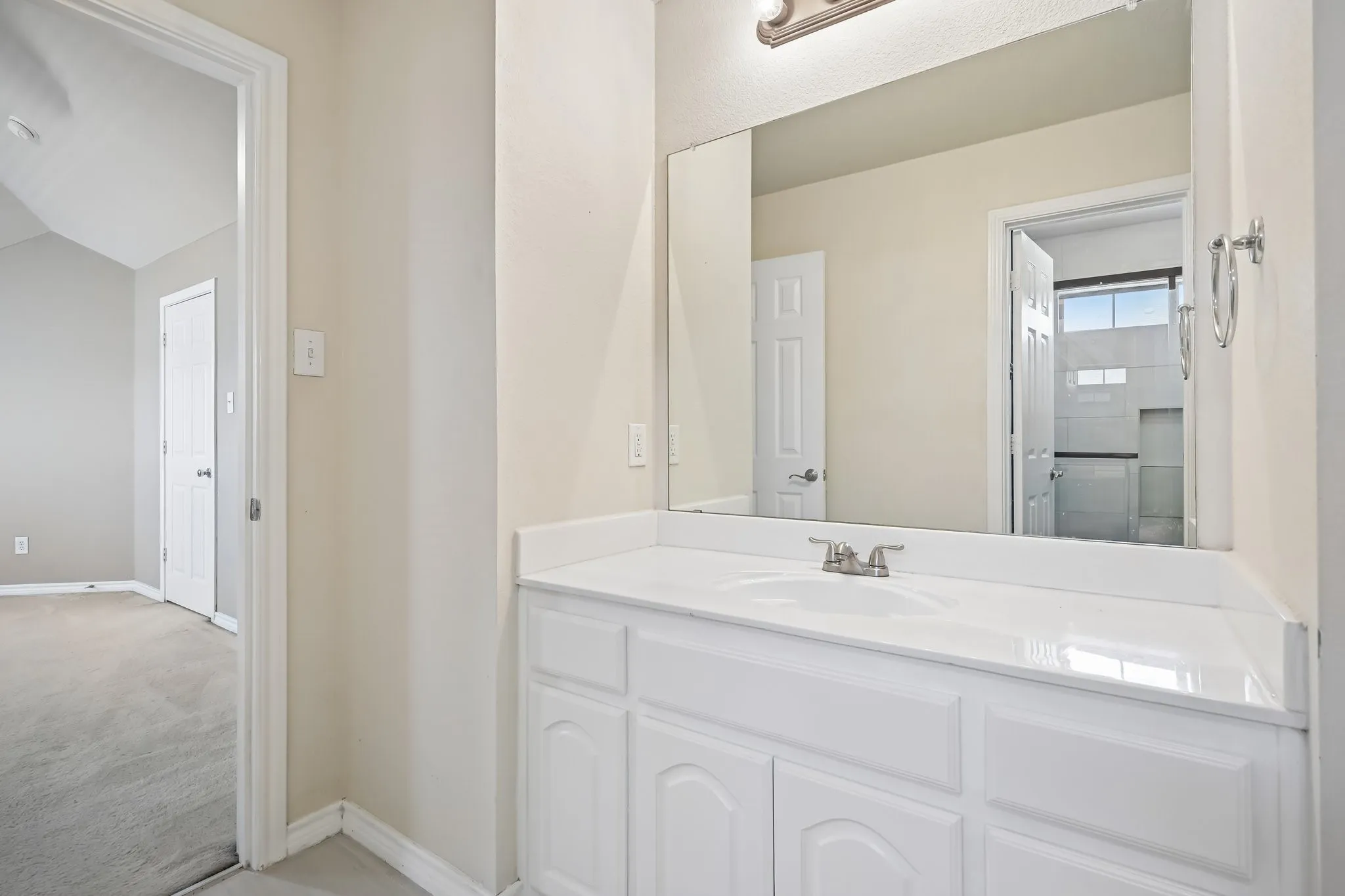 Bathroom vanity featuring a white countertop with integrated sink, brushed nickel faucet, and a large wall-mounted mirror