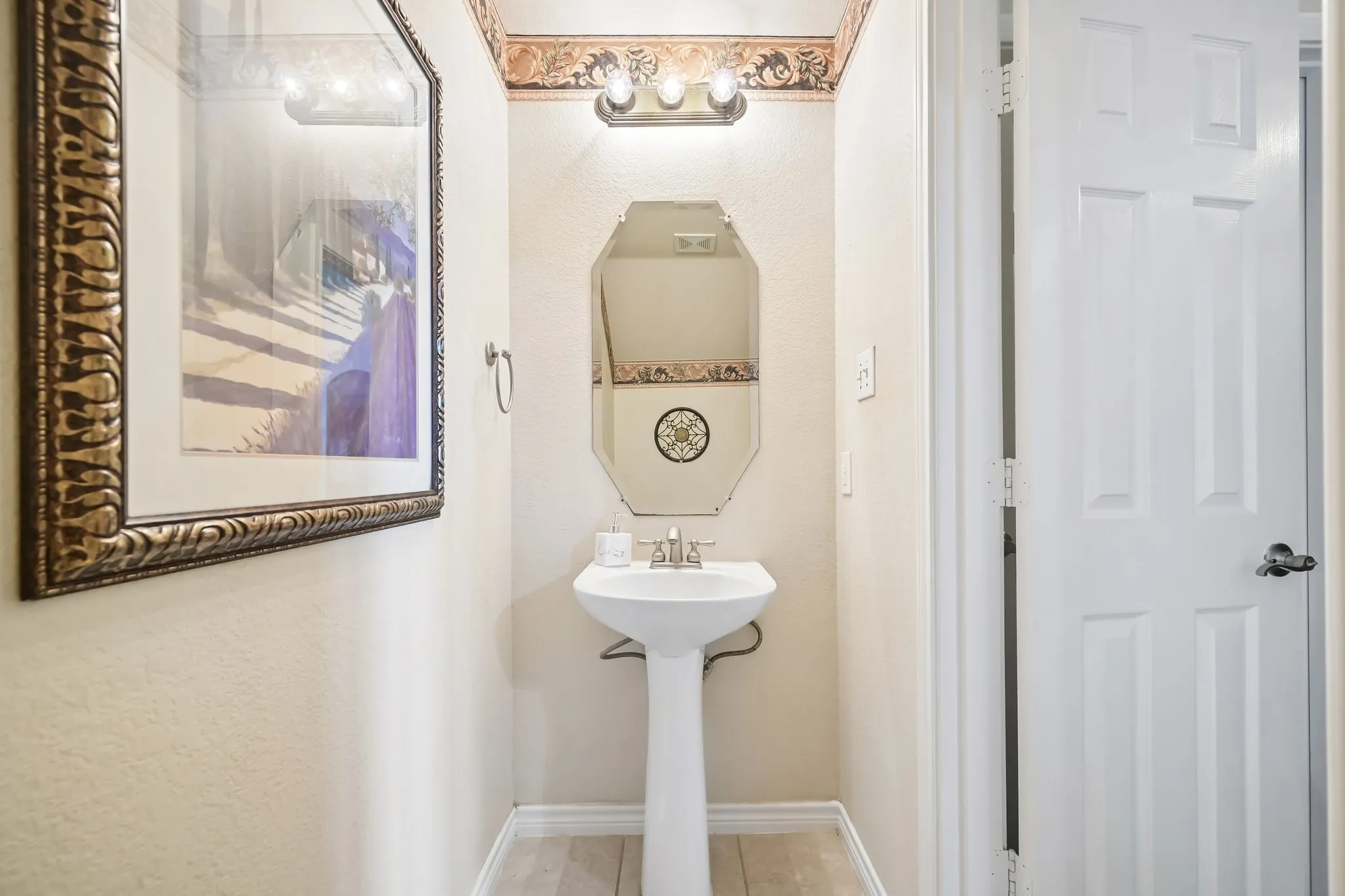 Pedestal sink with chrome faucet, octagonal mirror, and vanity light fixture