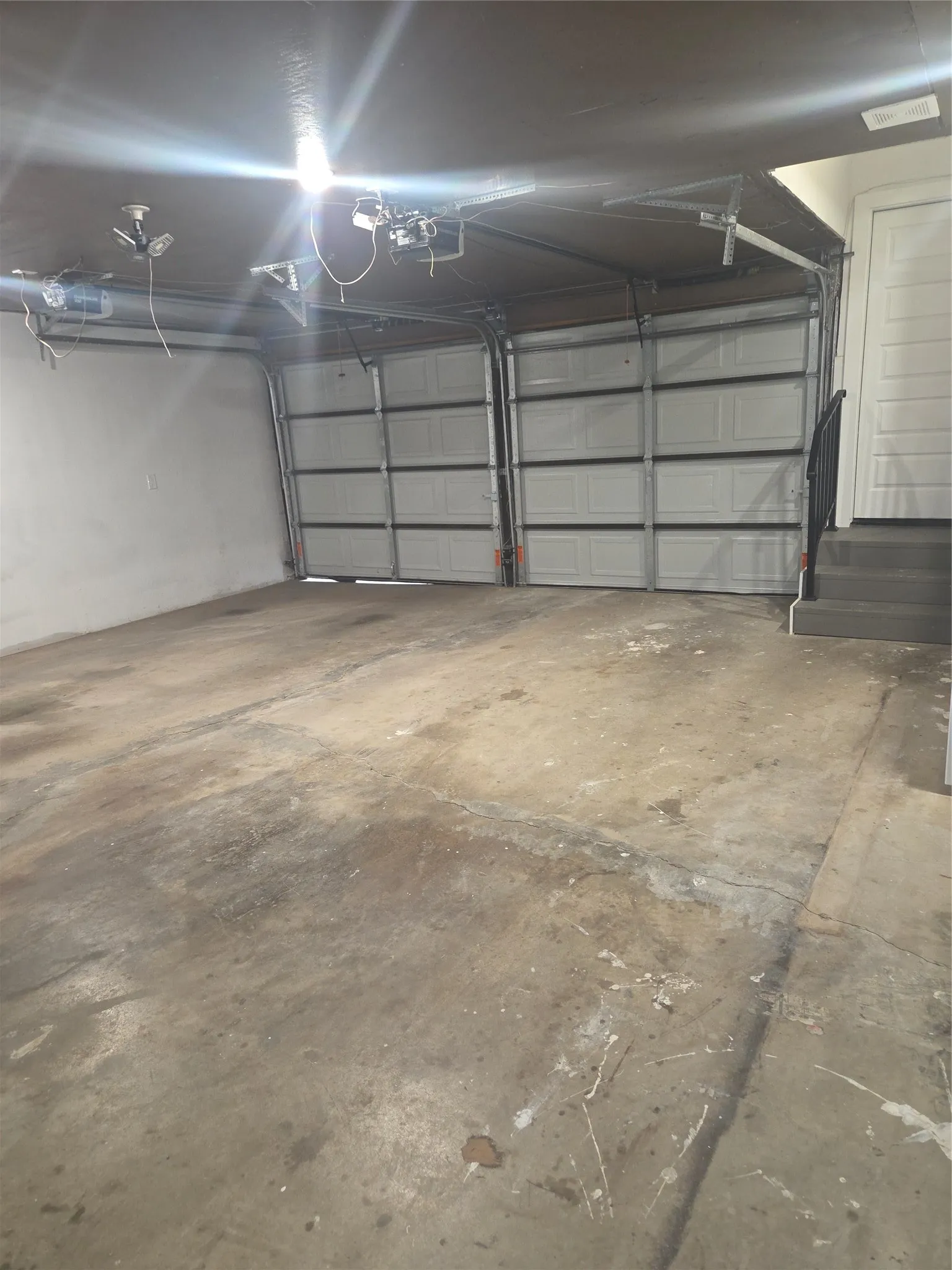 Two-bay garage featuring concrete flooring, overhead lighting, and an interior access door with steps