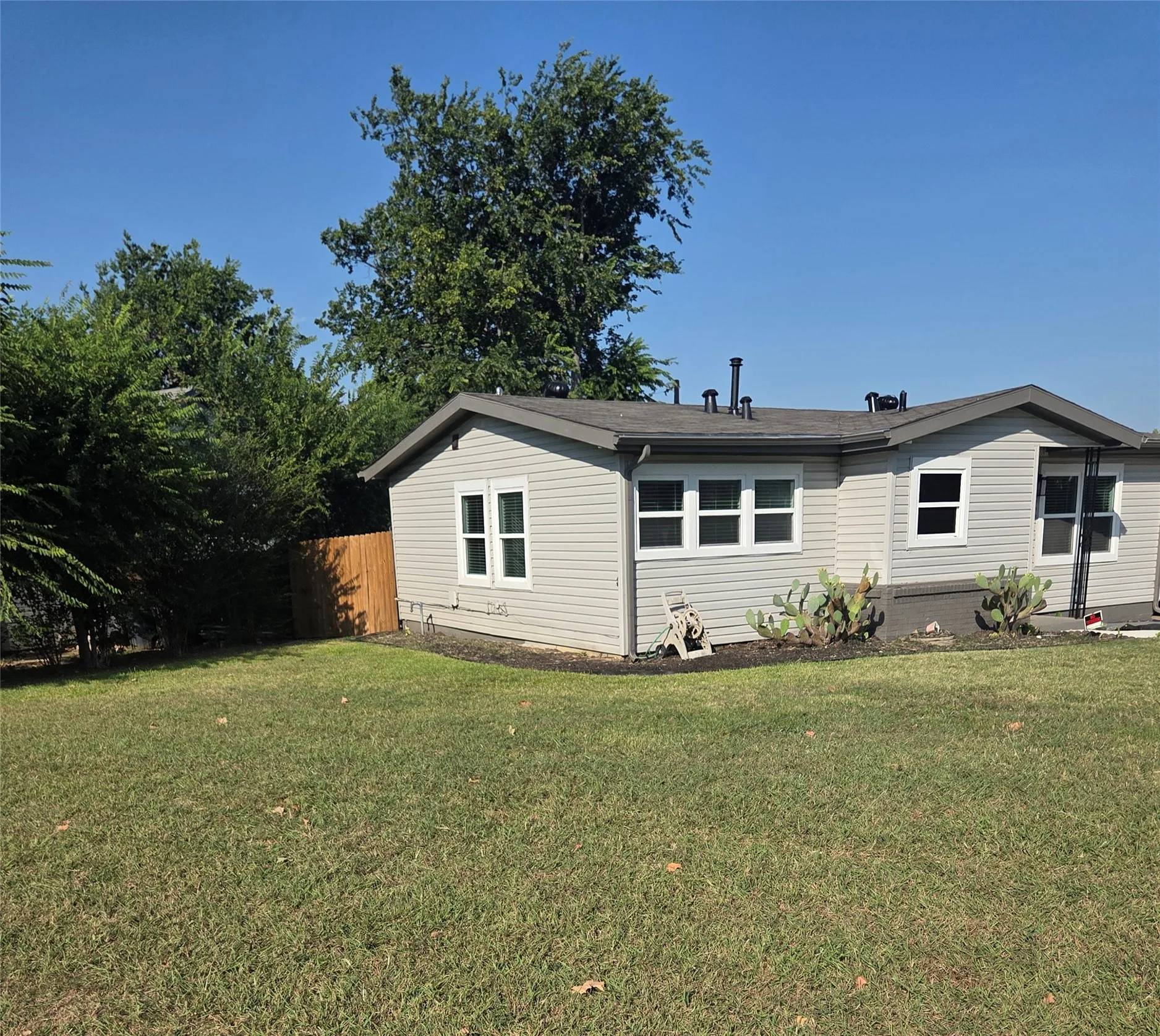 Exterior showcasing light gray horizontal siding, white-framed windows, and a dark gray roofline