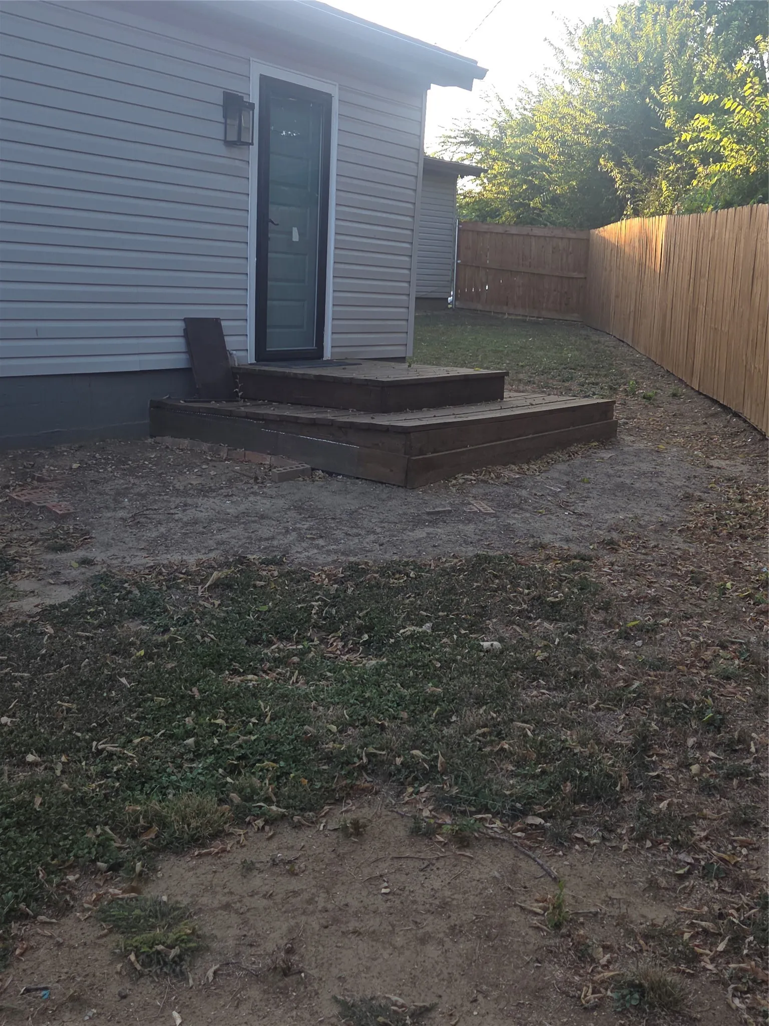 Rear exterior featuring horizontal siding, a wooden deck with two steps, and a privacy fence
