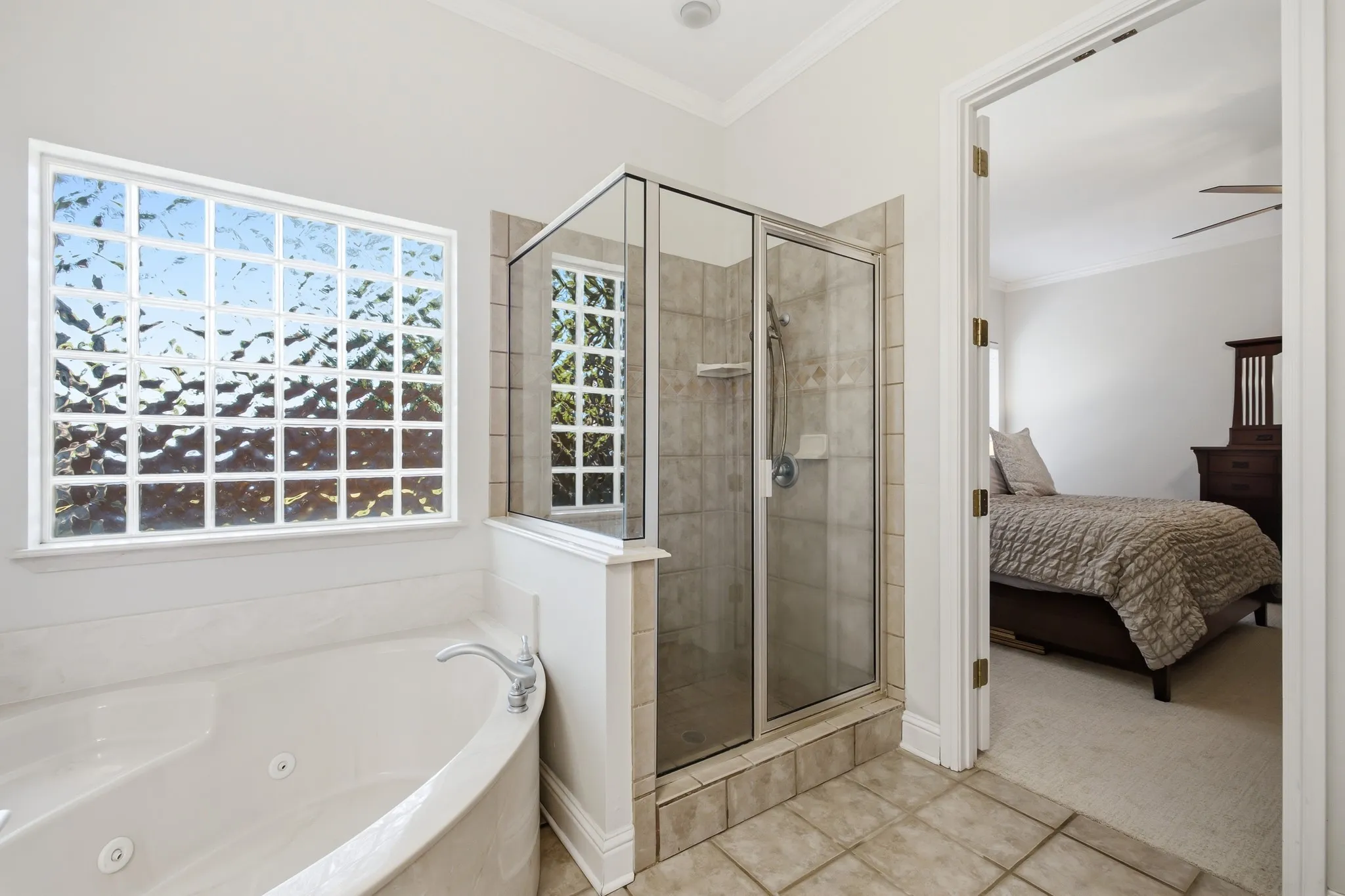 Bathroom featuring a built-in jetted tub, a separate glass-enclosed shower with tile surround, and a large privacy window