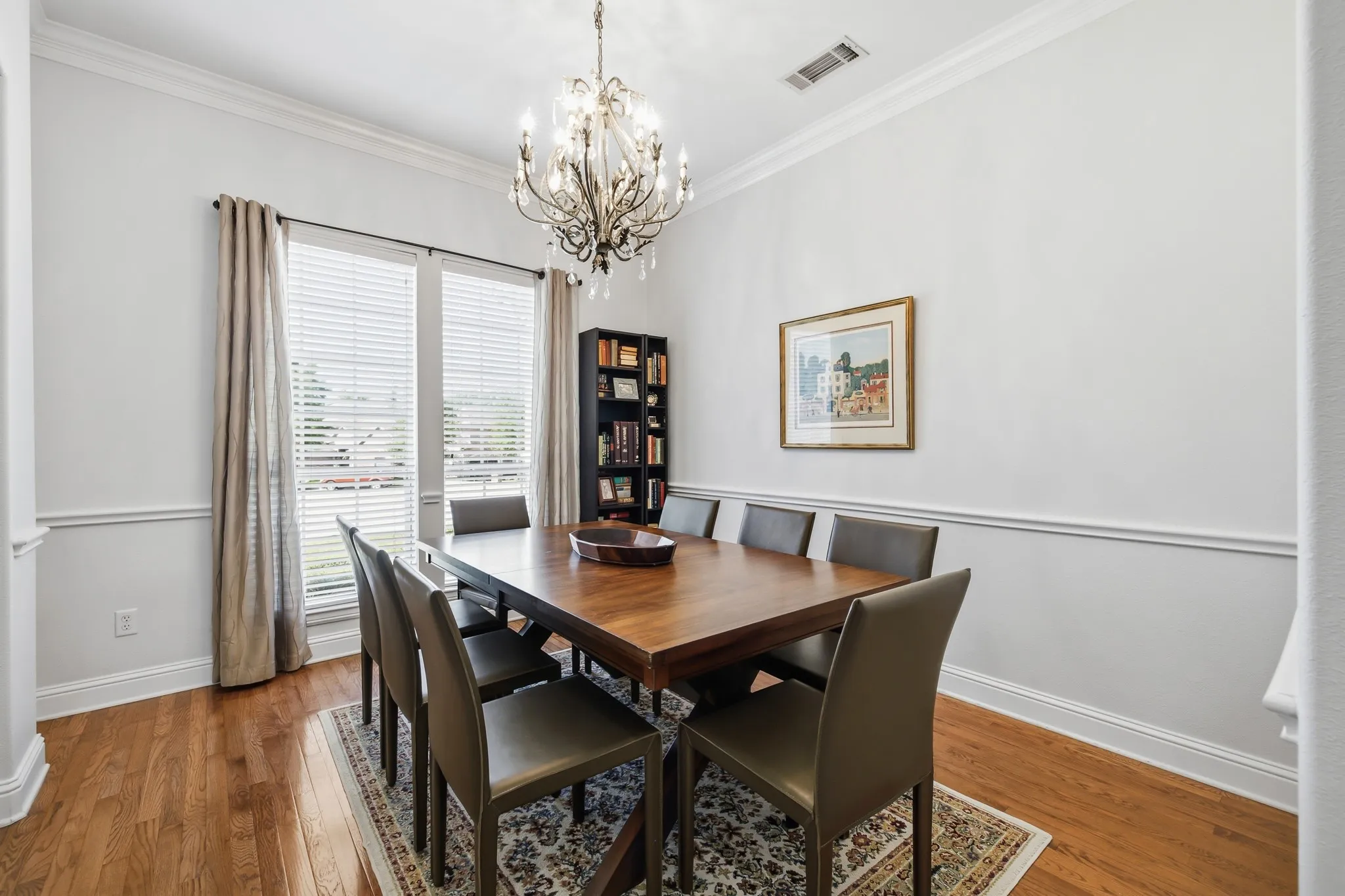 Formal dining space featuring hardwood flooring, crown molding, and wainscoting