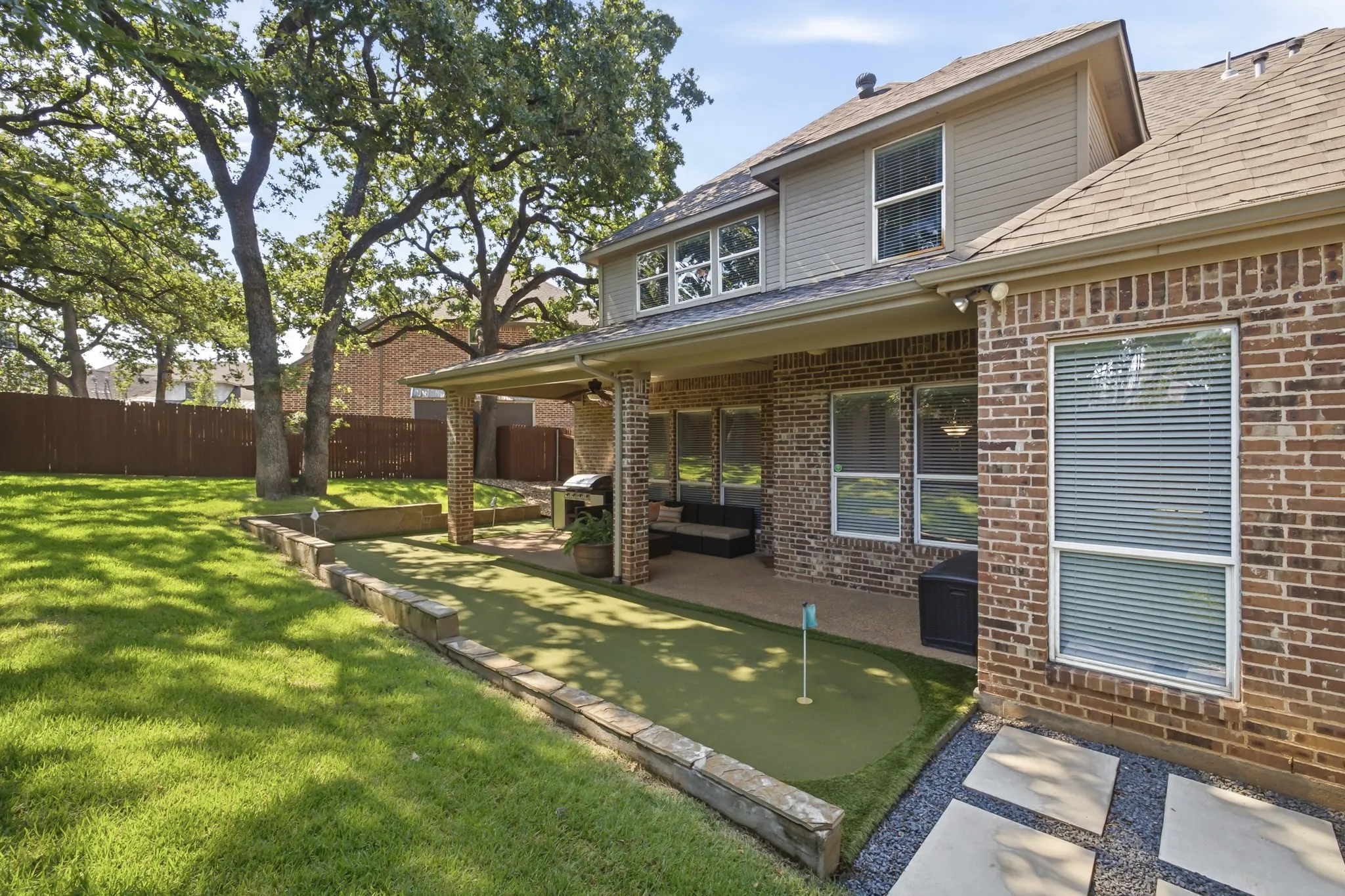 Expansive backyard featuring a putting green, covered patio, and mature trees