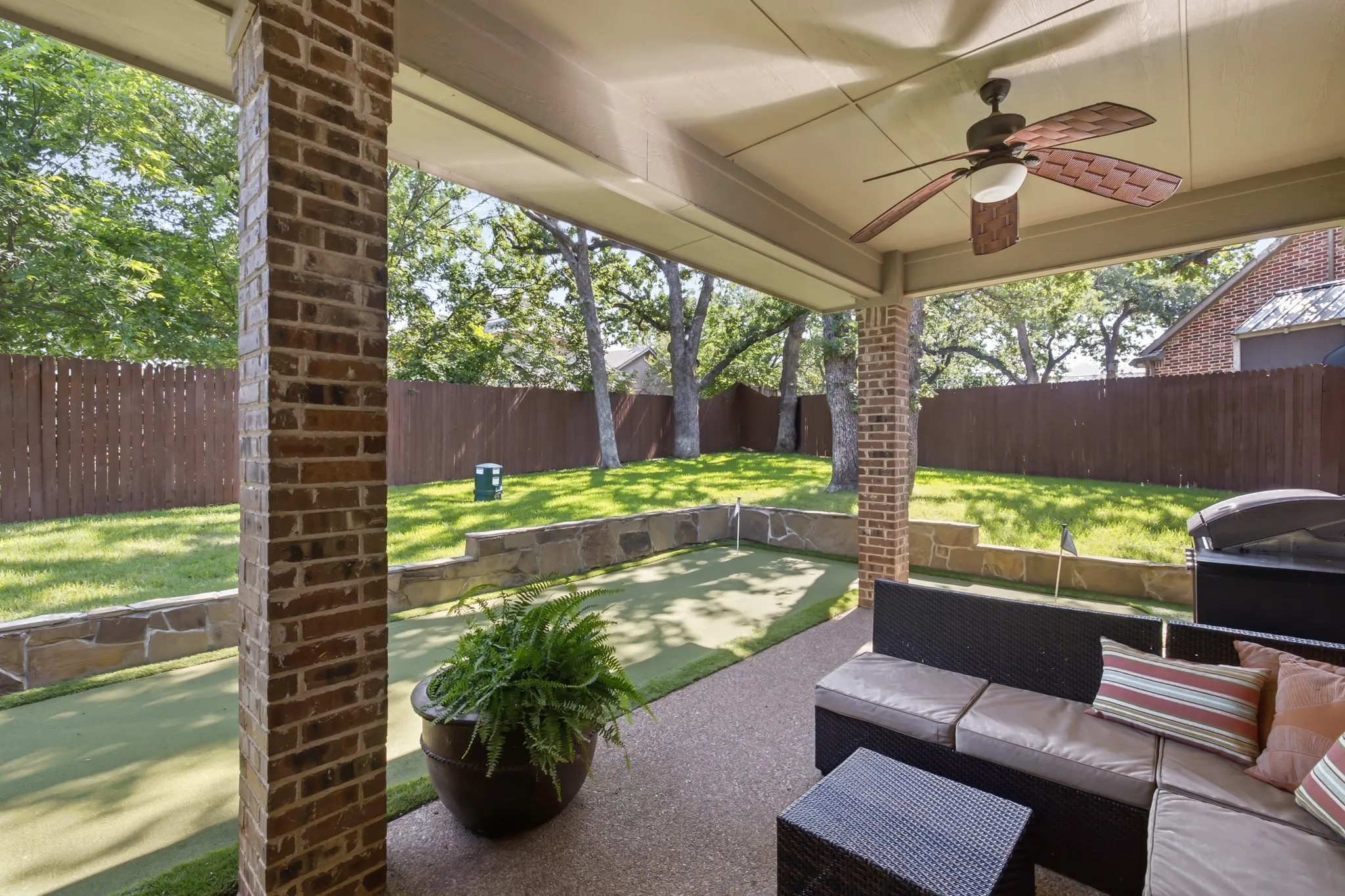 Covered patio featuring brick support columns, a ceiling fan with integrated lighting, and textured concrete flooring