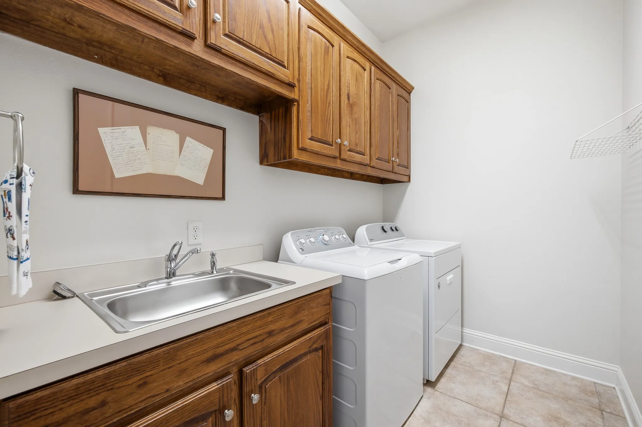 Laundry room featuring wood cabinetry, a utility sink and tile flooring