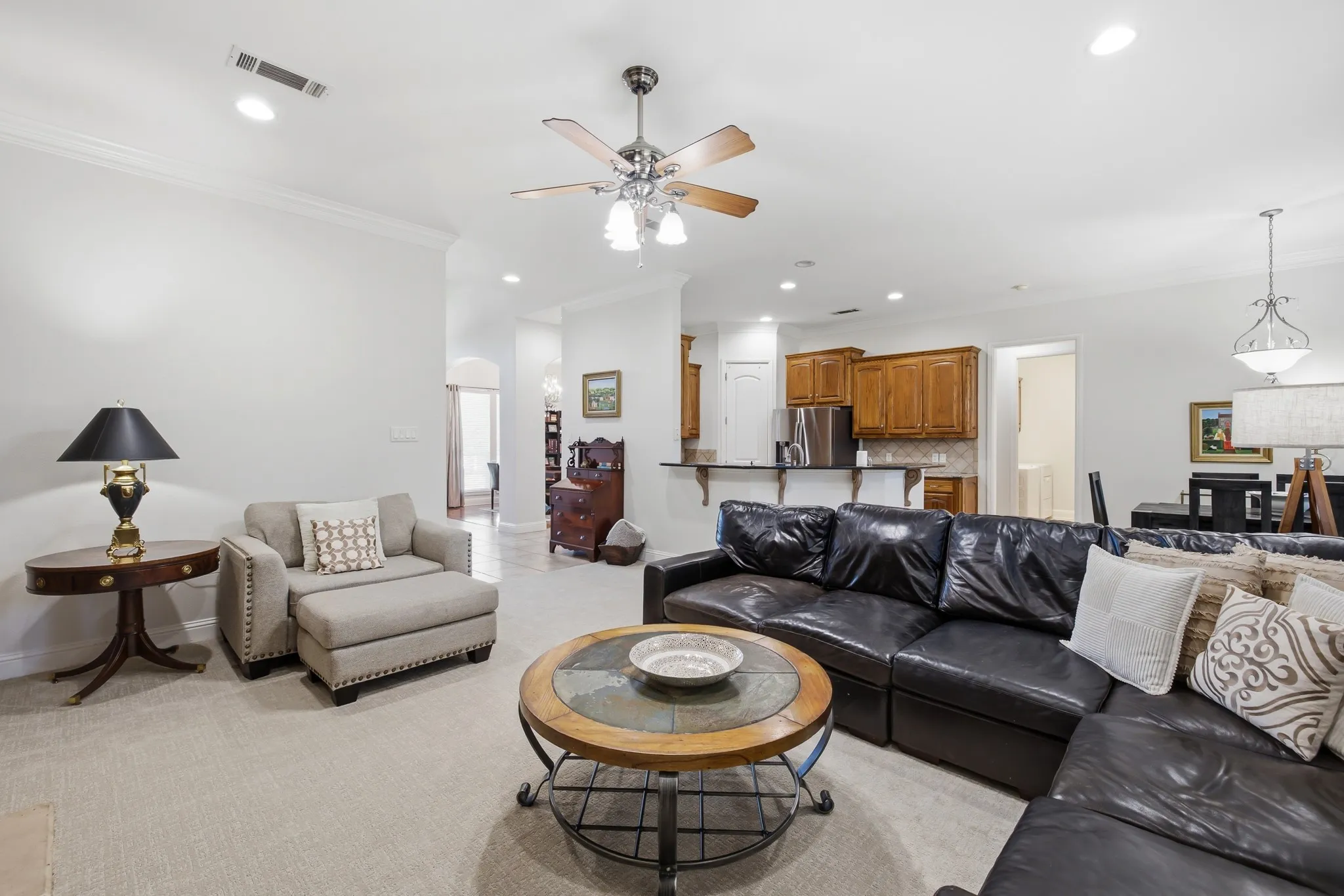 Open-concept living area featuring light-colored carpeting, recessed lighting, and a ceiling fan