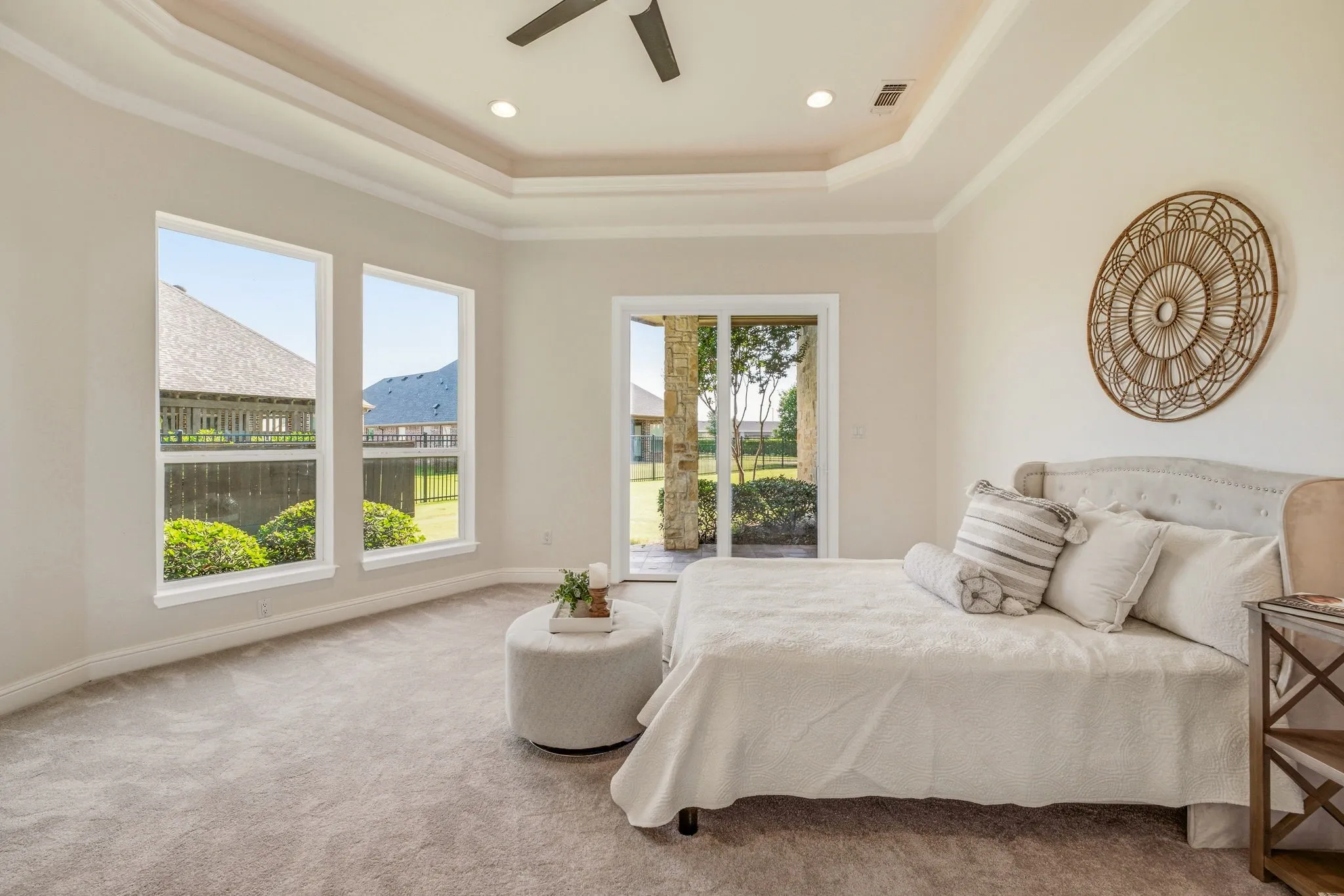 Spacious primary bedroom featuring a tray ceiling with recessed lighting and a ceiling fan