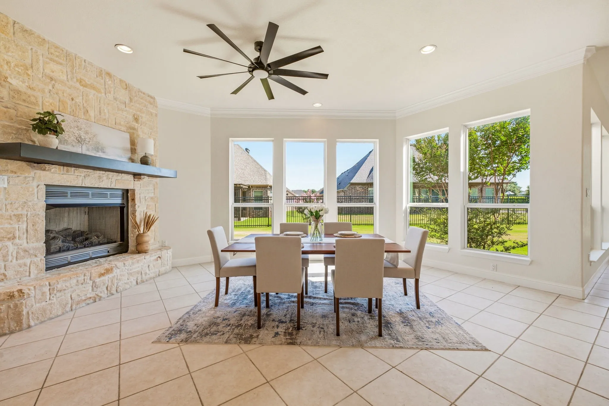 Dining area featuring a stone-clad fireplace with a dark wood mantel, a multi-paneled ceiling fan, recessed lighting, and multiple windows