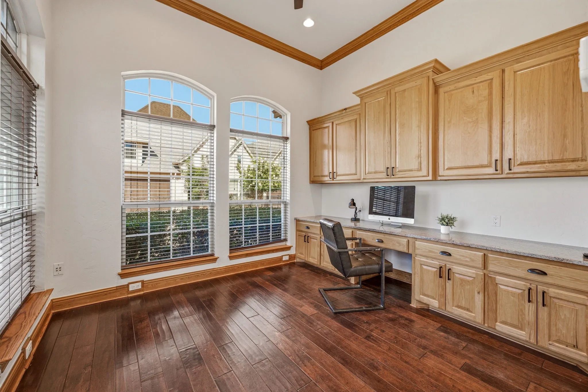 Dedicated workspace featuring extensive light wood cabinetry with dark hardware, a built-in desktop, and ample storage