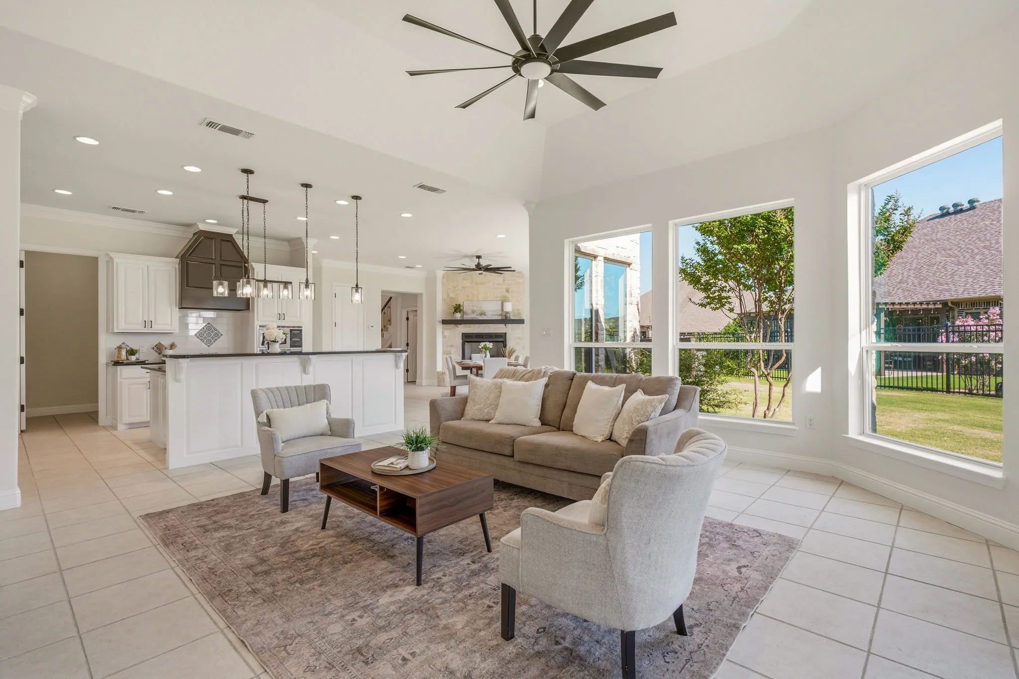 Spacious living area featuring a vaulted ceiling with a modern ceiling fan, large windows, and tile flooring