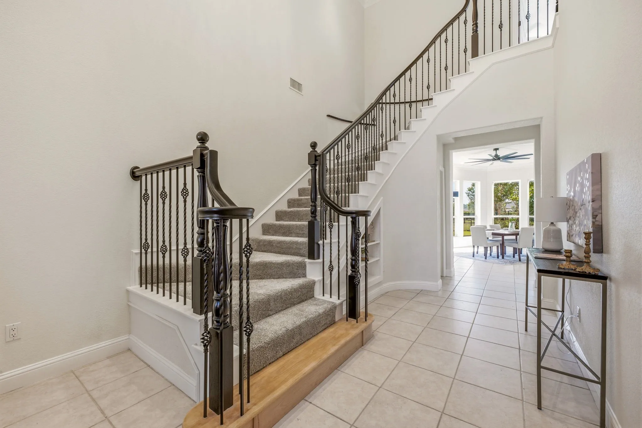 Grand staircase featuring wrought iron balusters and carpeted treads