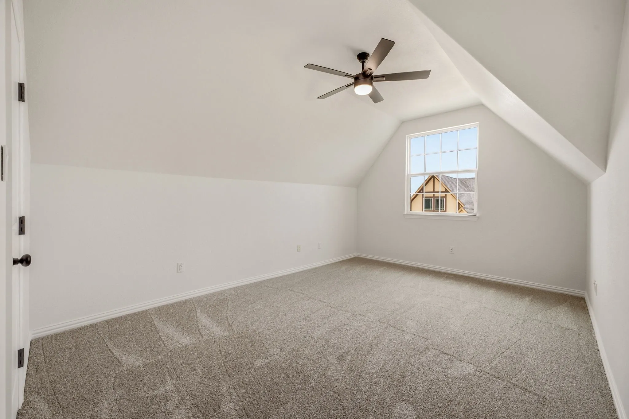 Spacious room featuring vaulted ceilings, a ceiling fan with integrated lighting, a single pane window, and plush carpet flooring