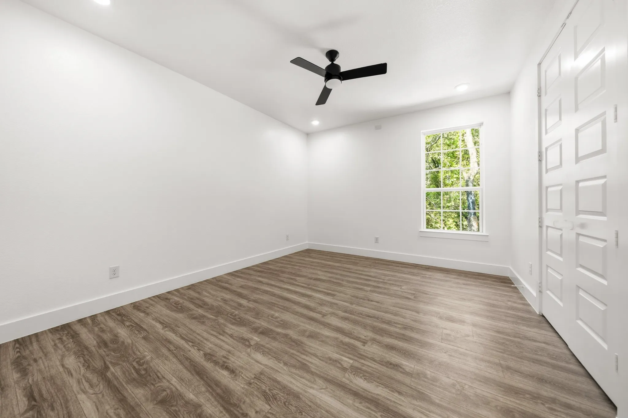 Spacious room featuring wood-finish flooring, recessed lighting, and a contemporary ceiling fan