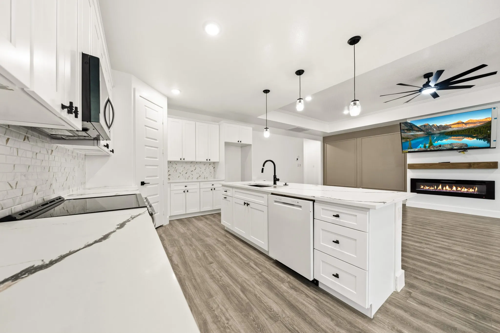 Modern kitchen featuring white cabinetry, a large center island with a sink, and light-toned wood-finish flooring