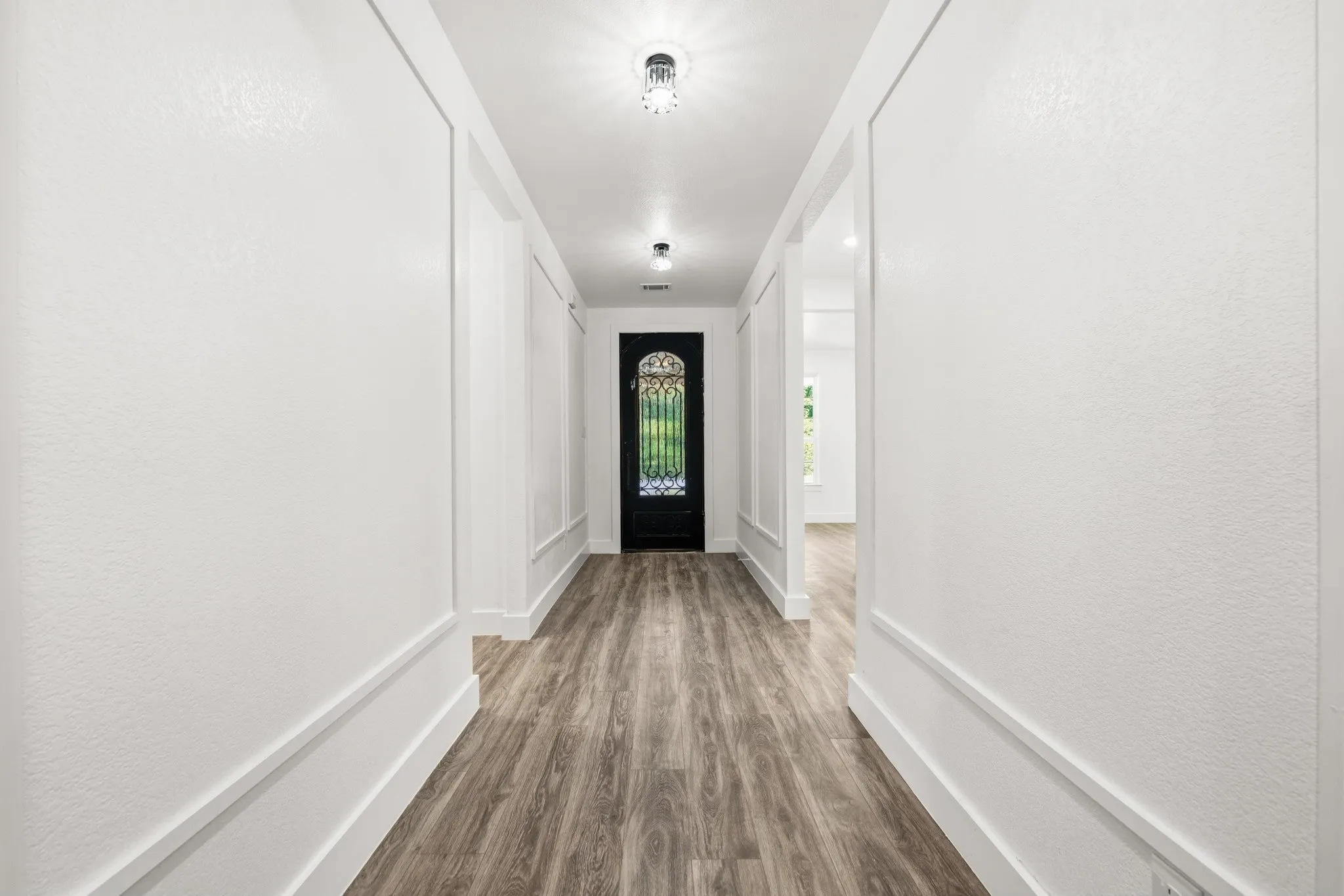 Entryway featuring a decorative front door with ironwork and glass paneling, wood-finish flooring, recessed lighting, and wainscoting